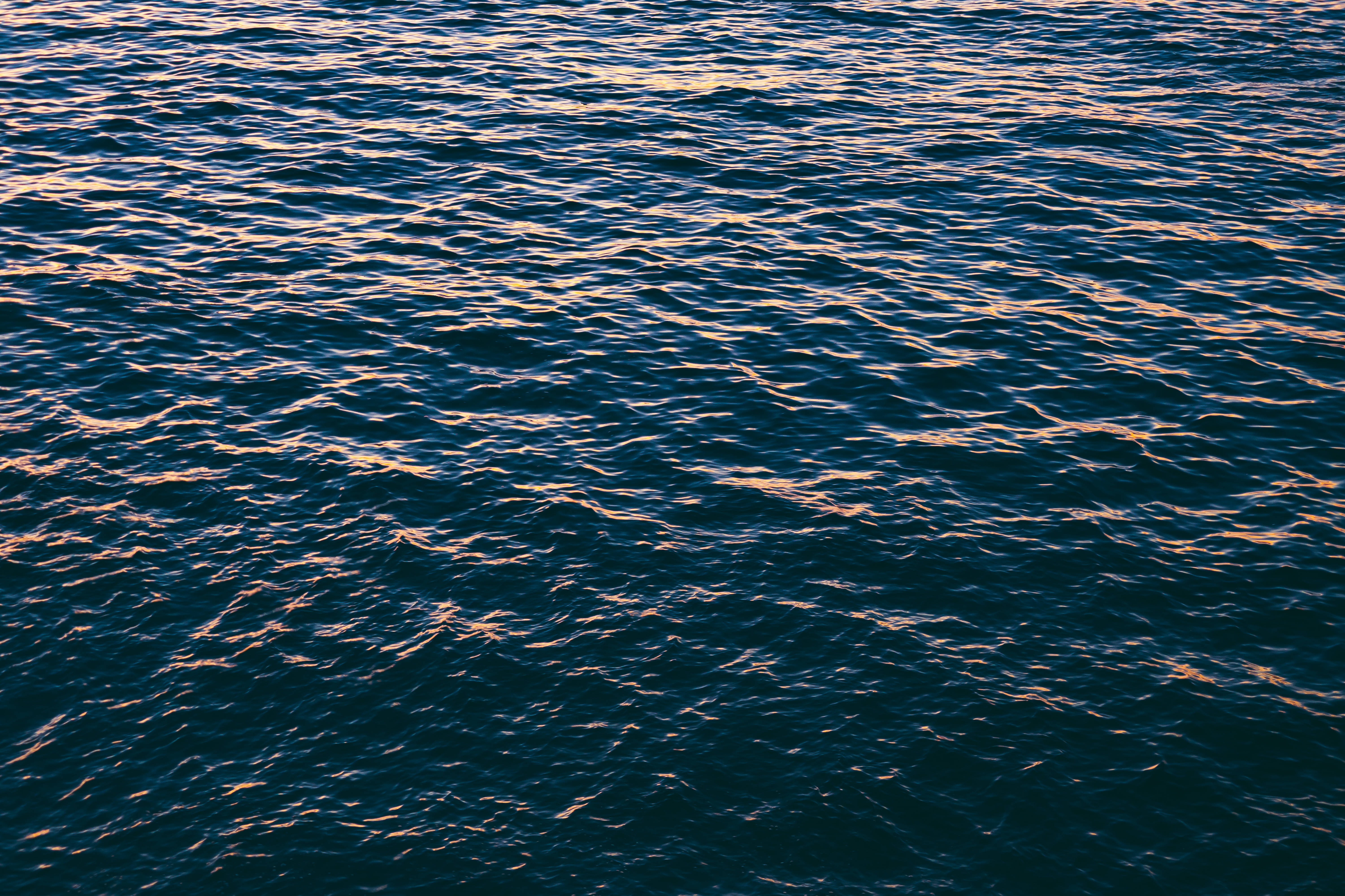 deep blue water, golden sunset light, shimmering textured surface, 5K Desktop Wallpaper