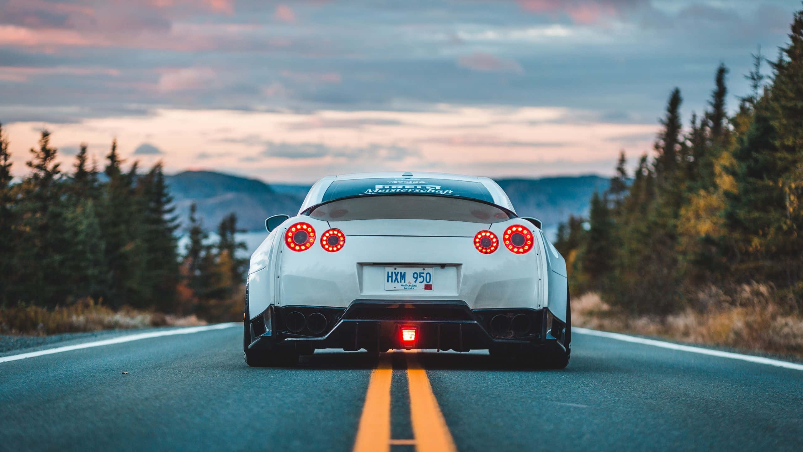 white sports car, glowing red taillights, forest-lined road, 2K Desktop Wallpaper