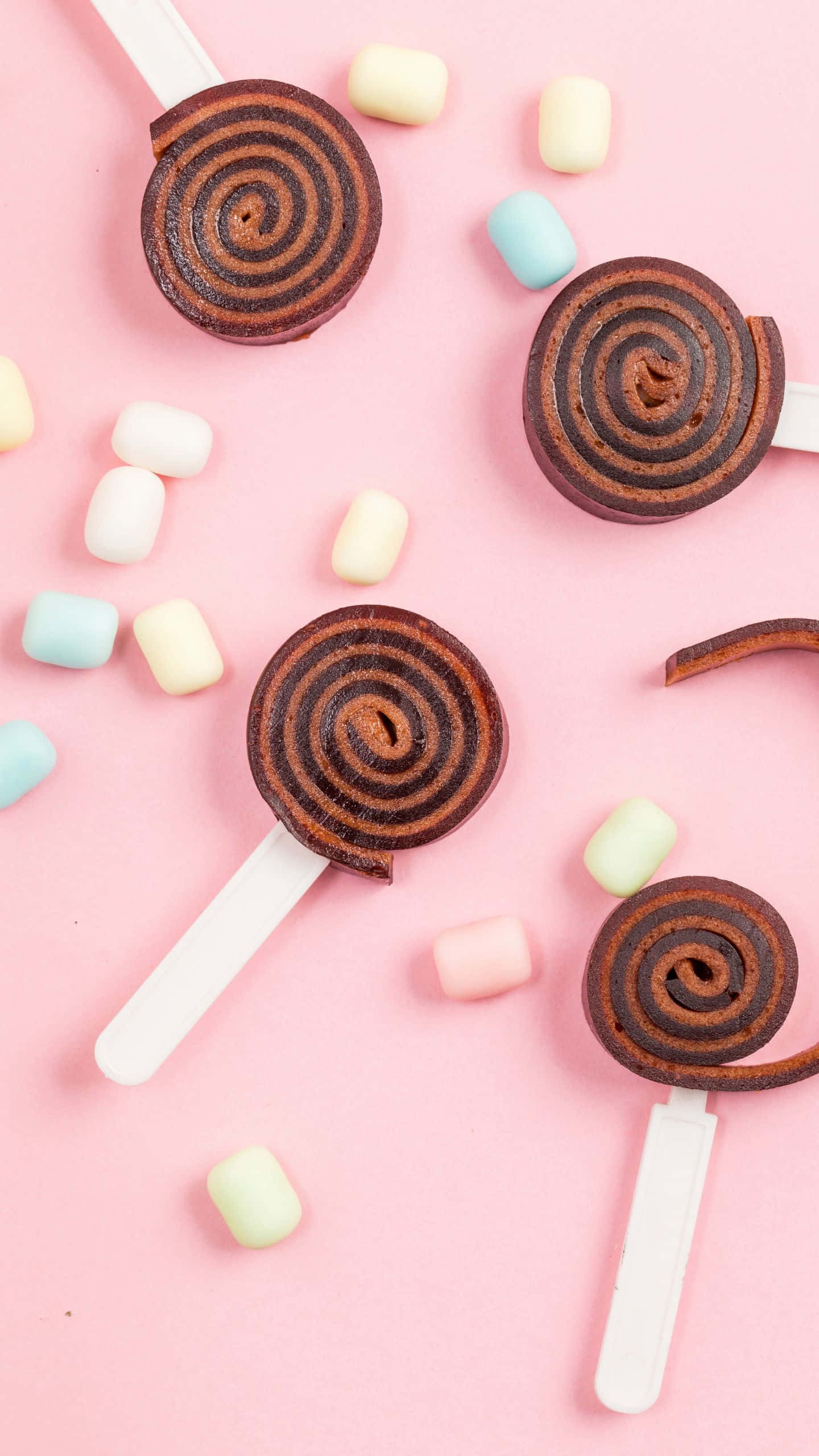 chocolate lollipops, pastel marshmallows, soft pink background, 2K Phone Wallpaper
