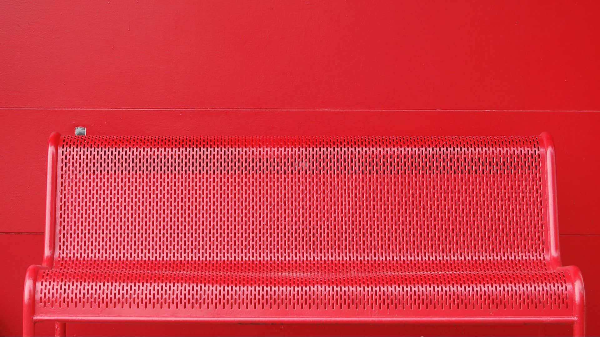 red perforated metal bench, matching red wall, minimalist urban setting, Full HD Desktop Wallpaper