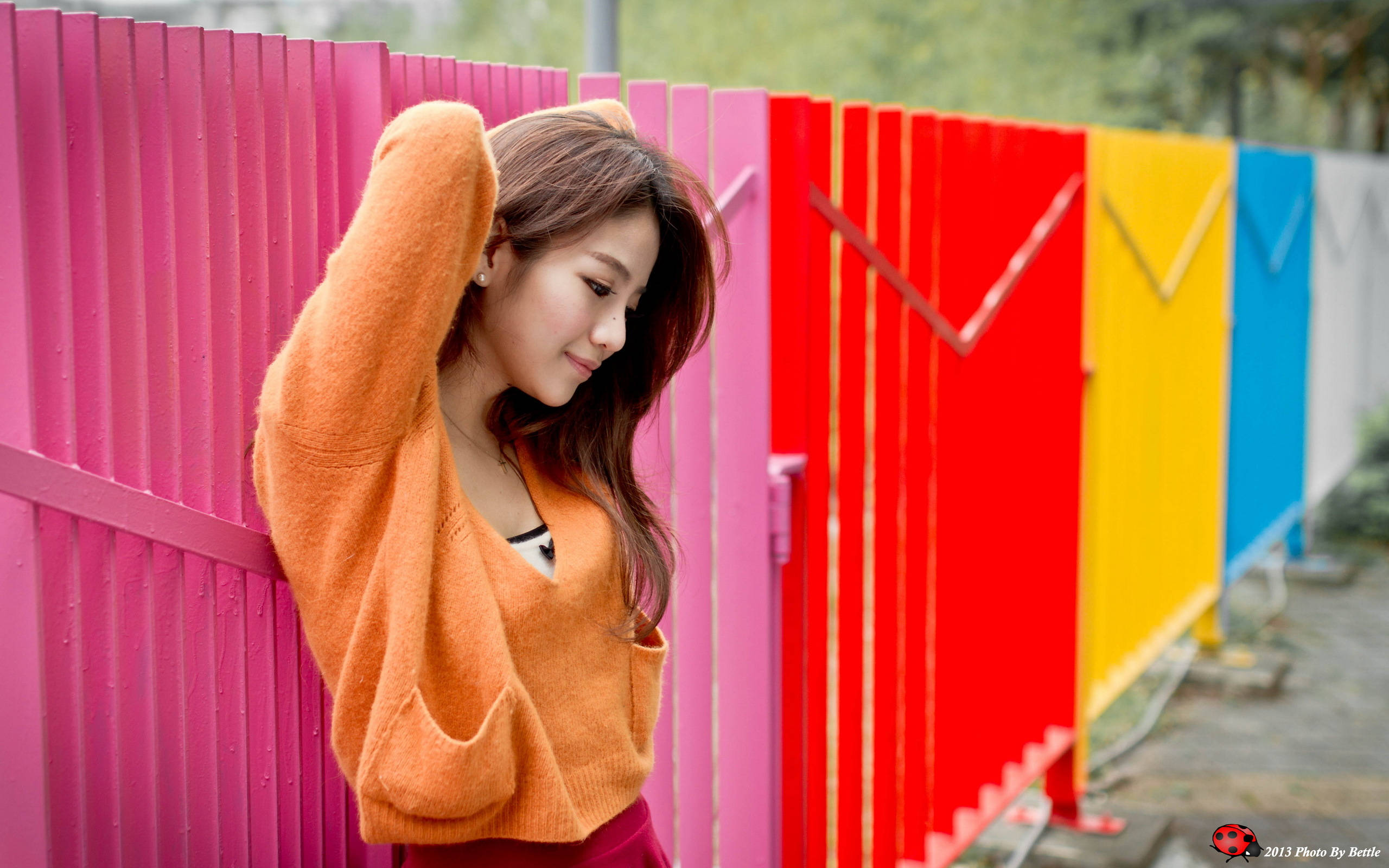 woman, orange sweater, vibrant rainbow-colored fence, 2K Desktop Wallpaper