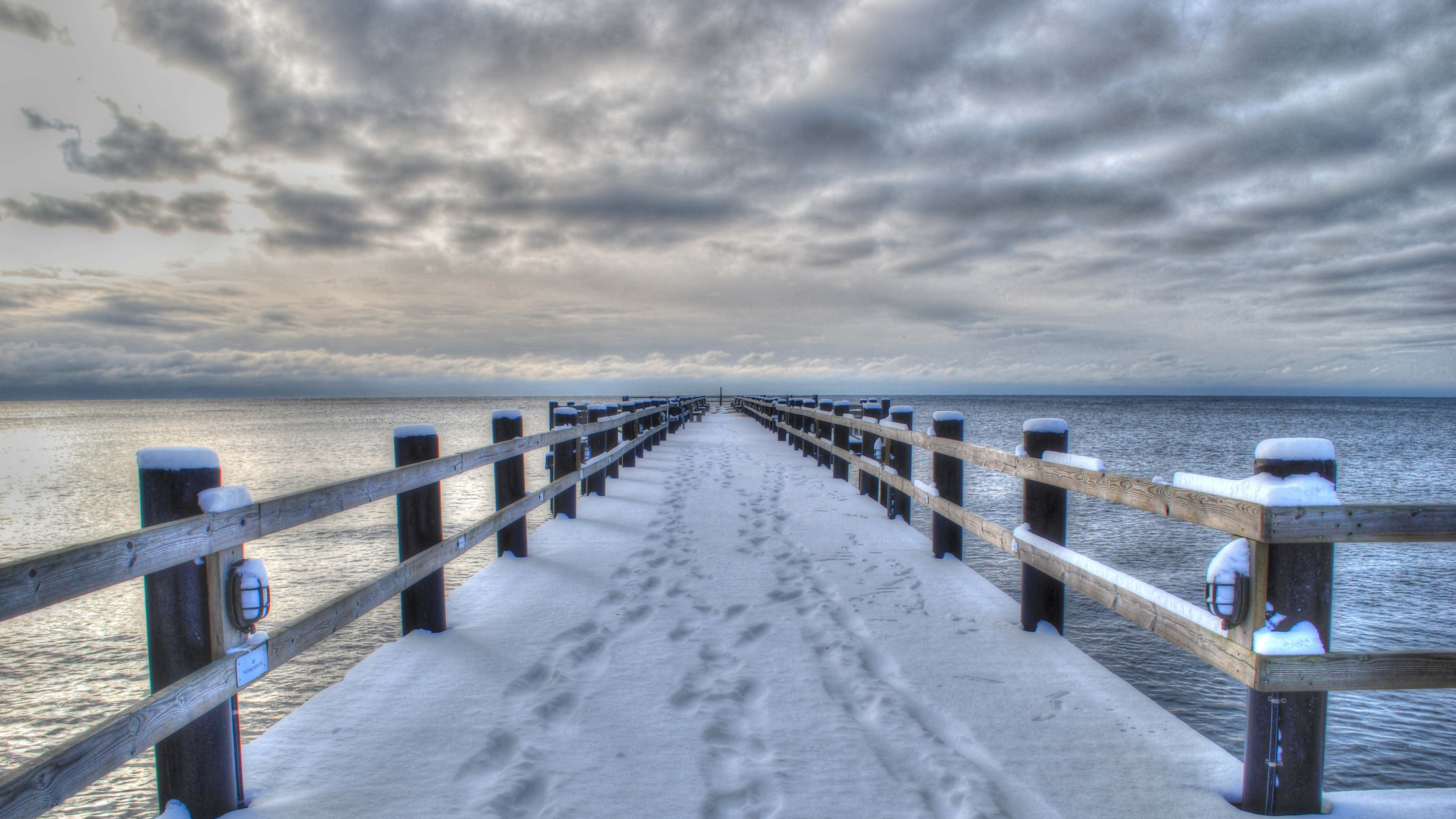 snow-covered wooden pier, calm waters, dramatic cloudy sky, 4K Desktop Wallpaper