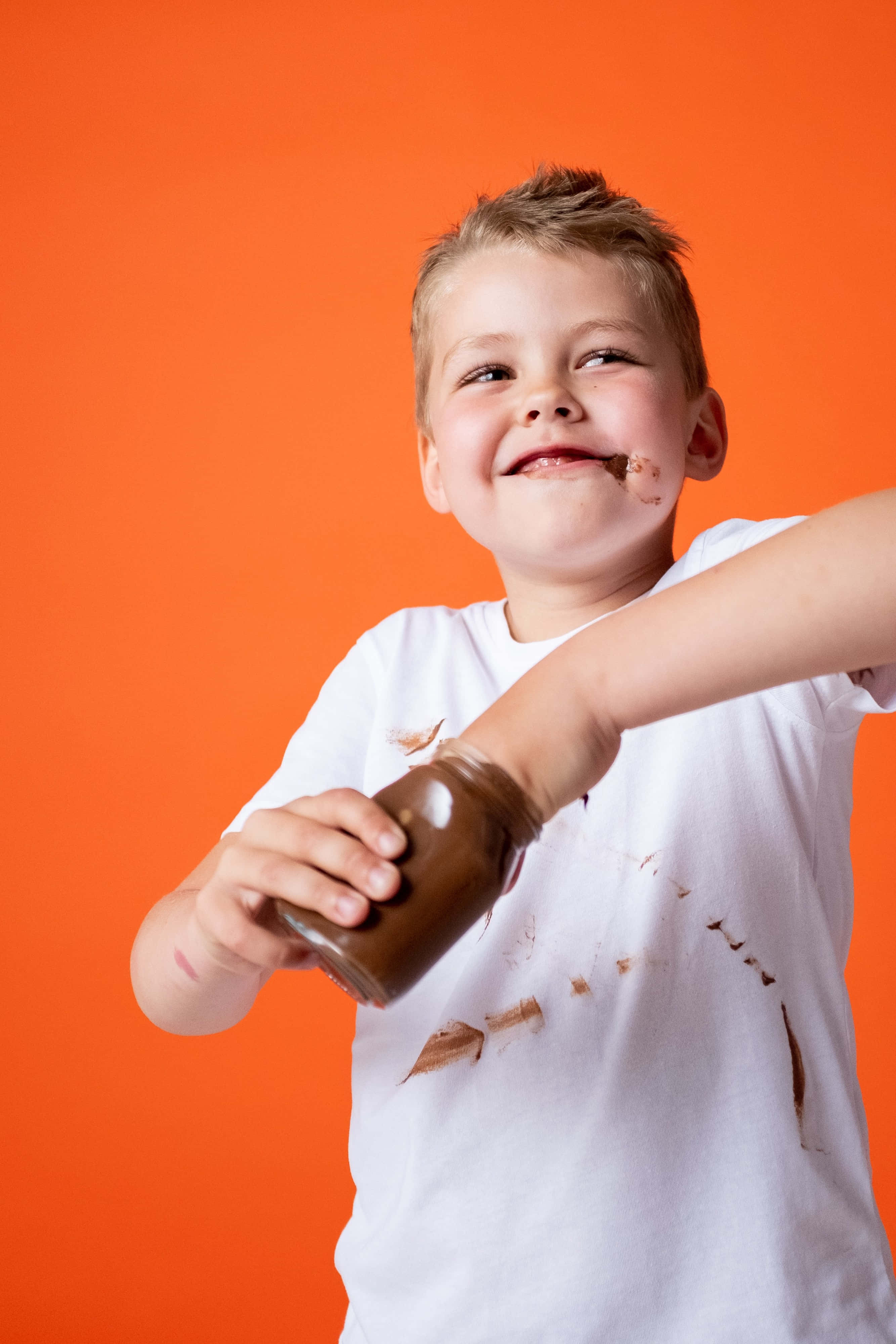 4K Boys Attitude, chocolate smeared on his face, vibrant orange background, 4K Phone Wallpaper