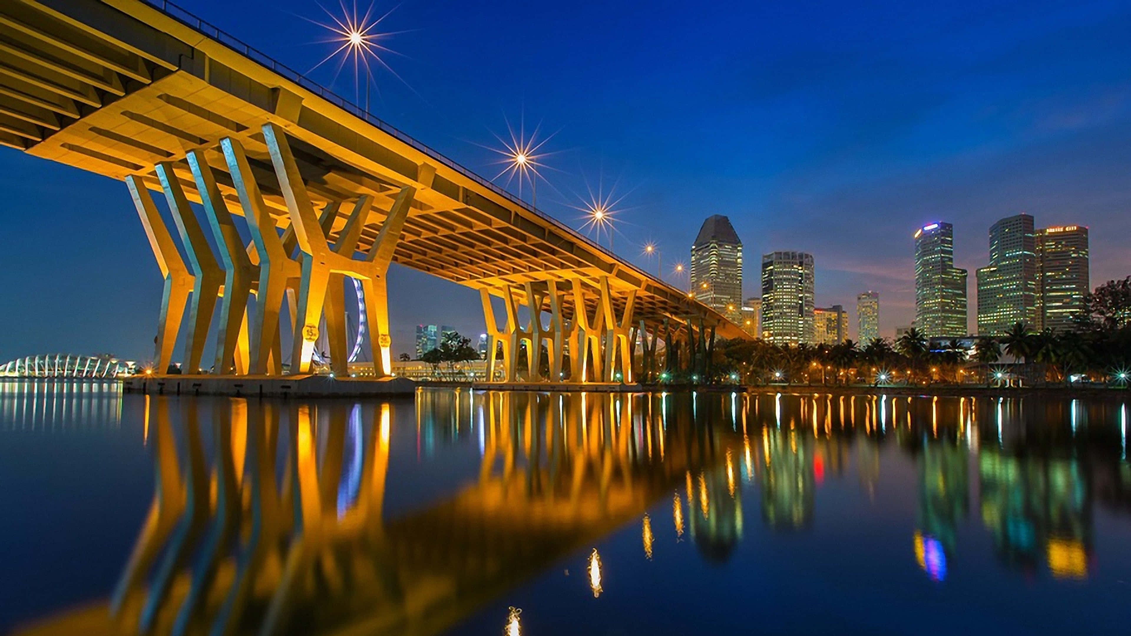 glowing yellow bridge, calm water, city skyline, 4K Desktop Wallpaper