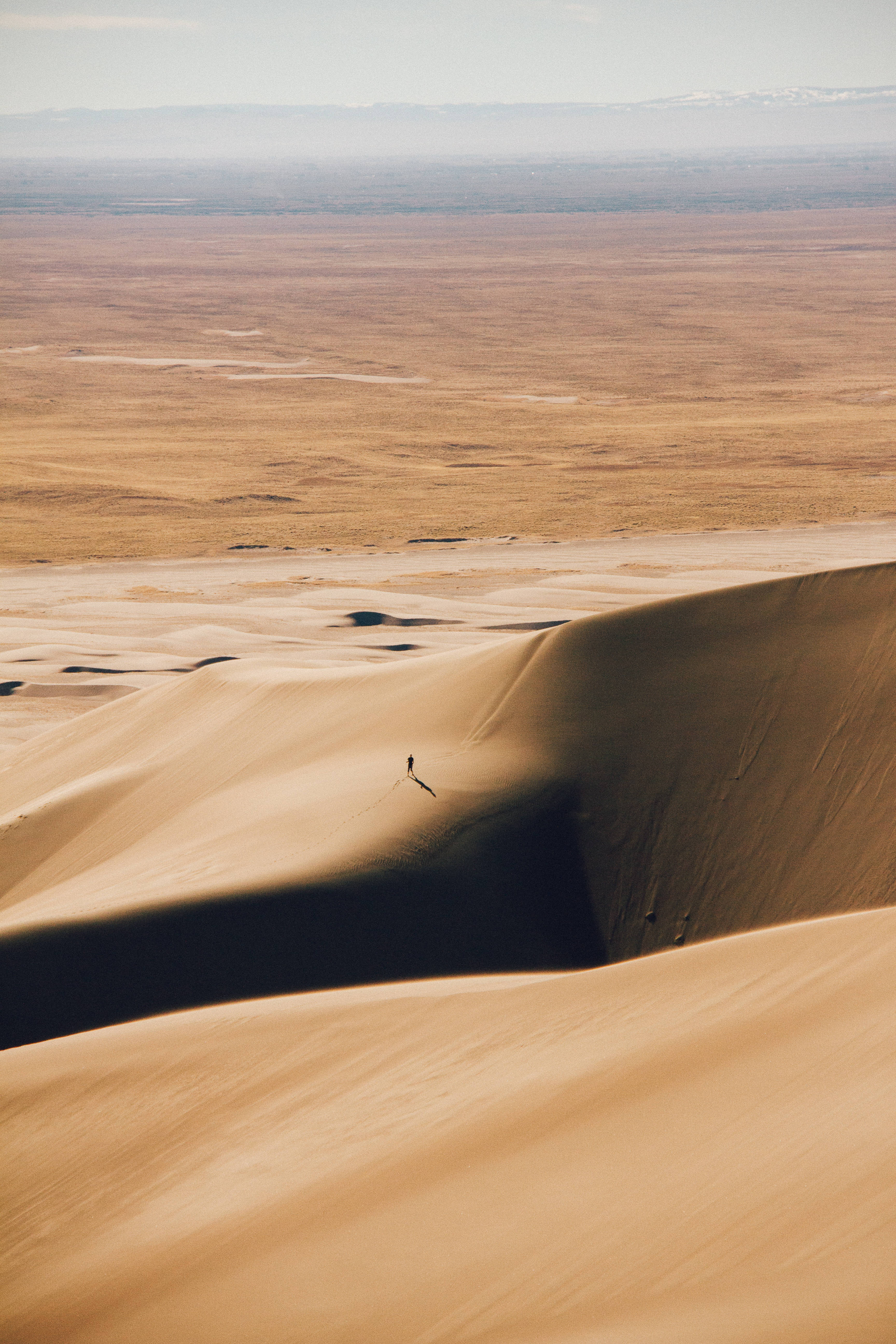 lone hiker, massive golden sand dune, hazy sky, 5K Phone Wallpaper