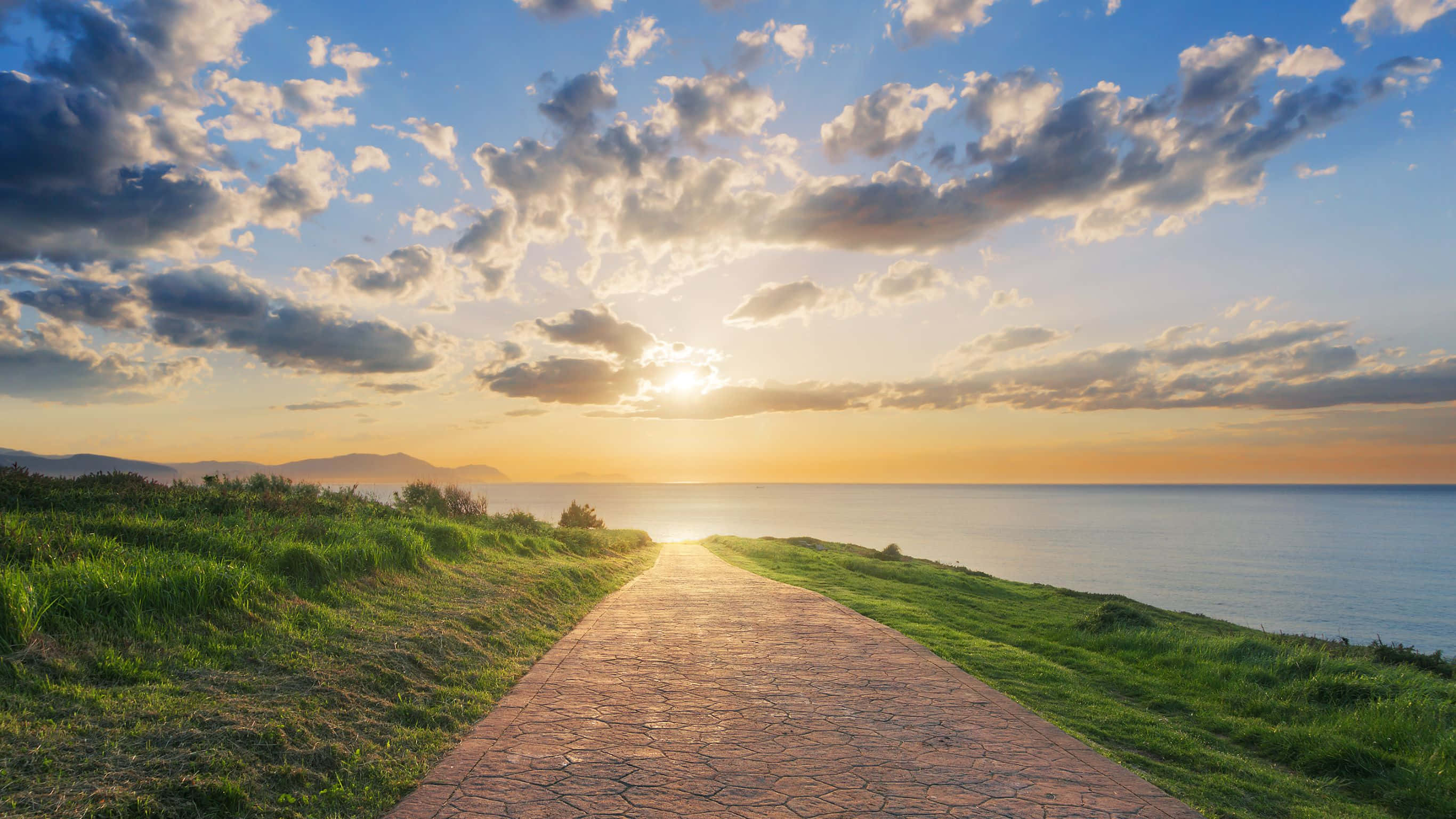 sunlit stone path, grassy dunes, glowing ocean horizon, 2K Desktop Wallpaper