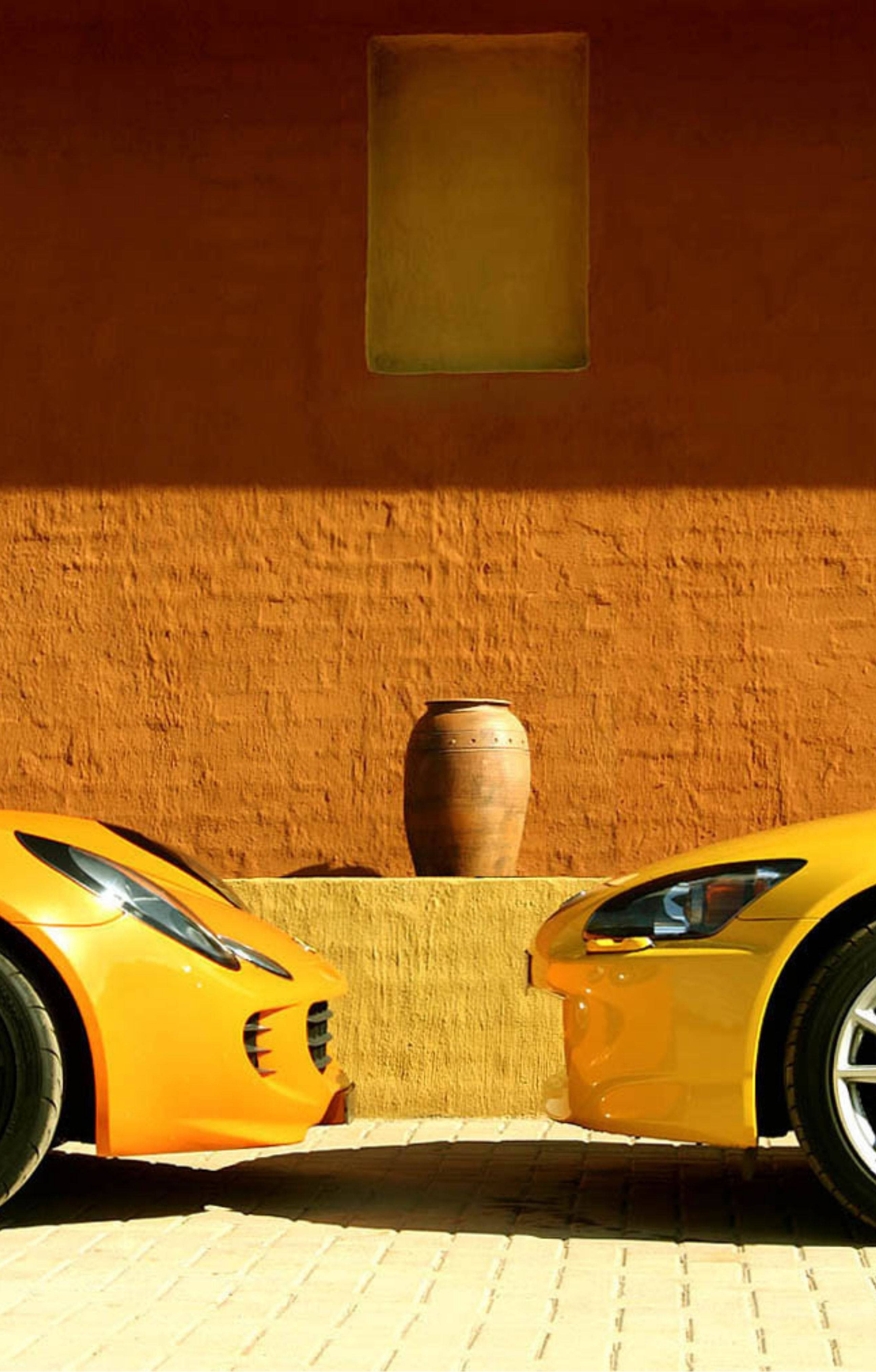 4K Lamborghini iPhone, Two vibrant yellow sports cars, textured terracotta wall, 4K Phone Wallpaper