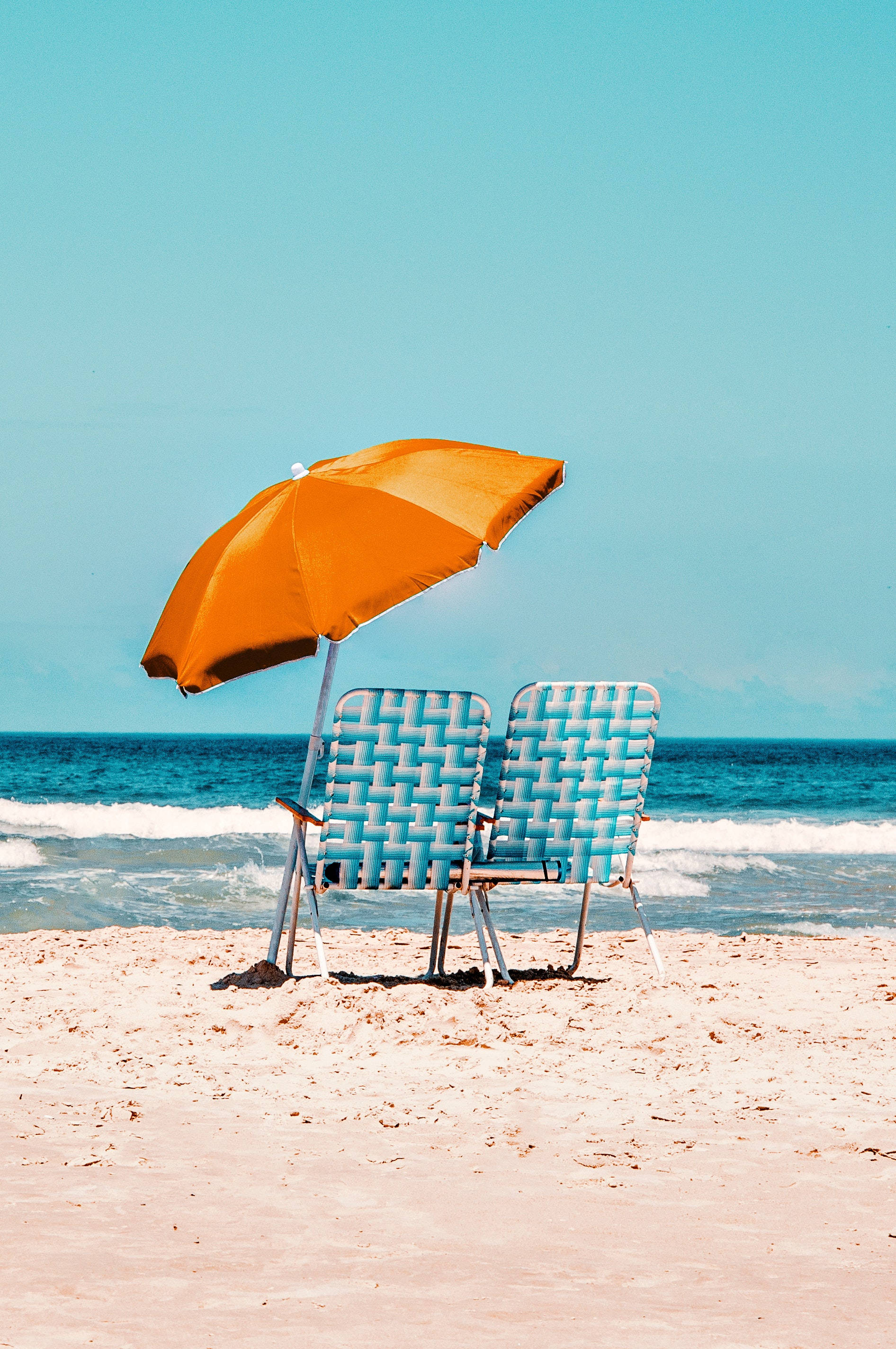 blue woven beach chairs, bright orange umbrella, sandy shore, 2K Phone Wallpaper