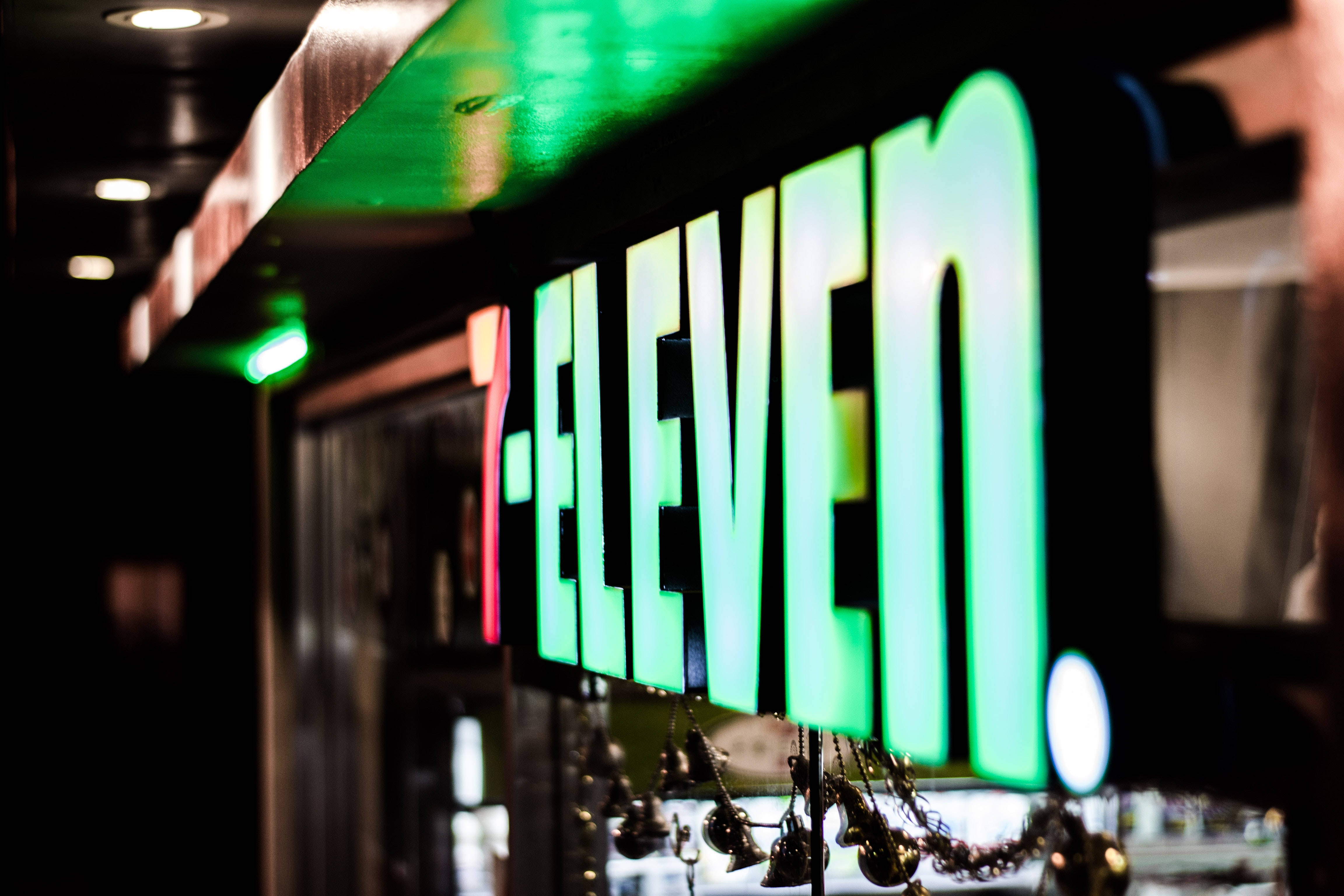 7-Eleven, glowing green sign, dark urban storefront, 4K Desktop Wallpaper