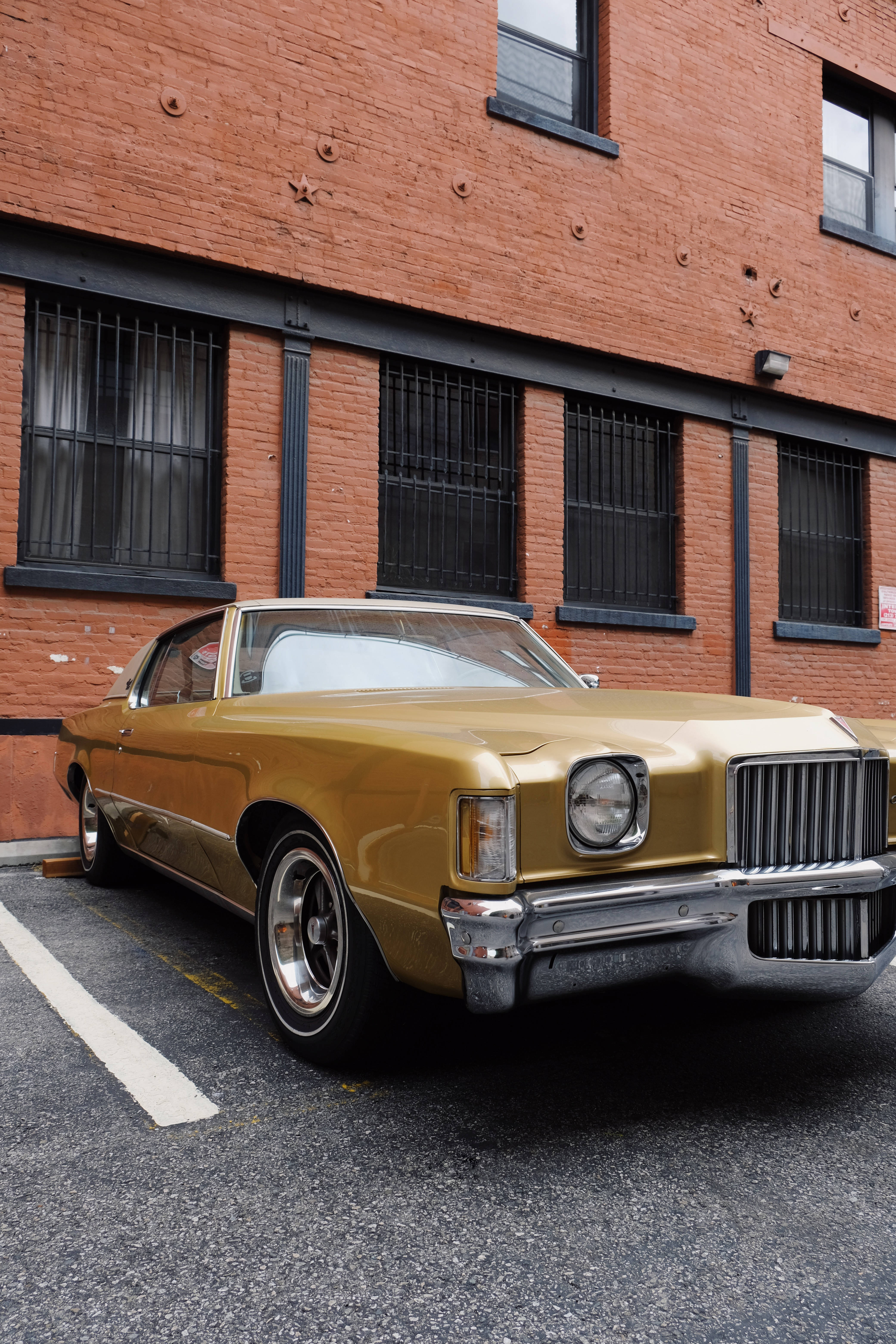 gold classic muscle car, weathered brick building, barred windows, 5K Phone Wallpaper