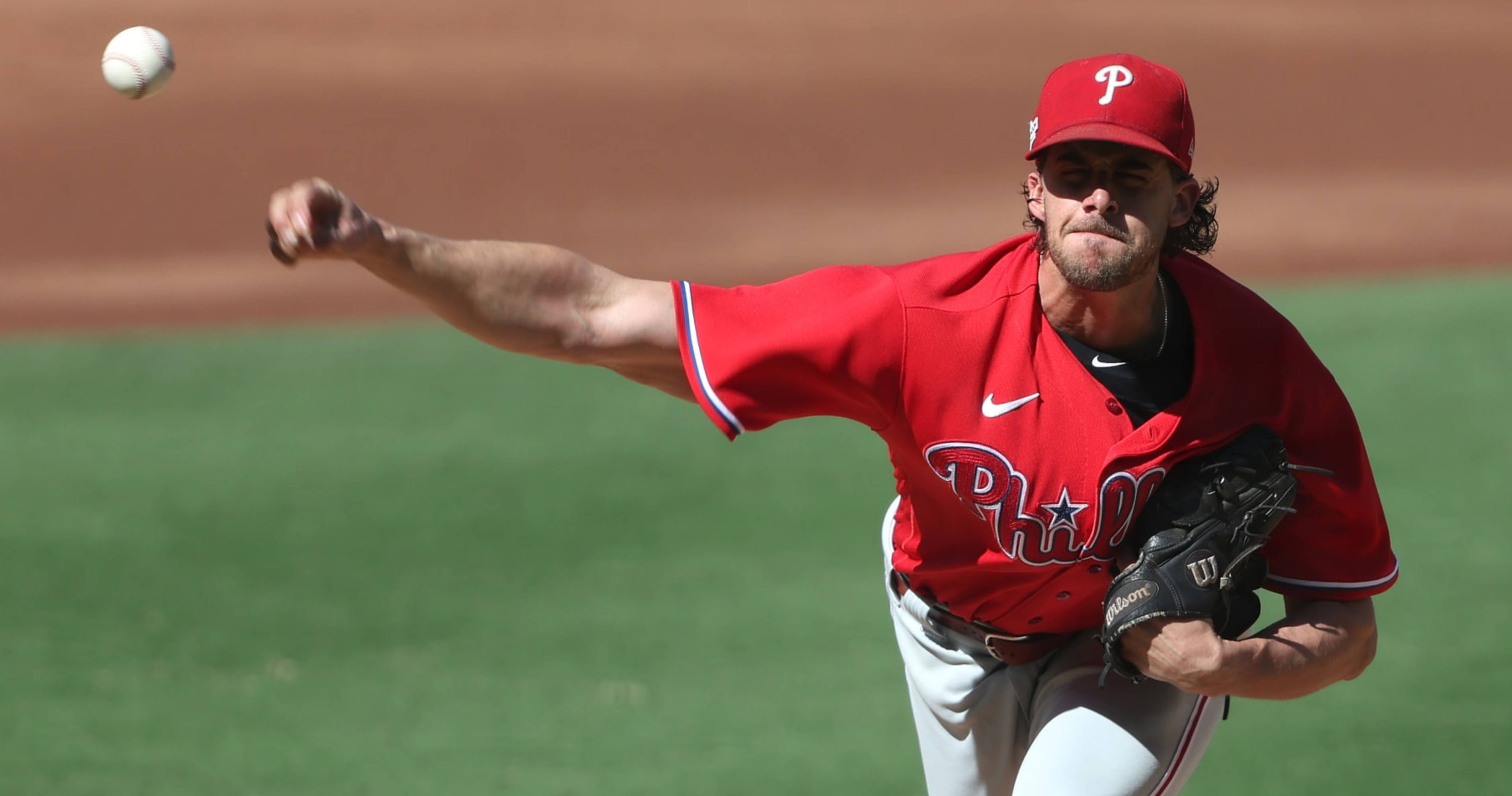 Aaron Nola, red Philadelphia uniform, sunlit field, 2K Desktop Wallpaper