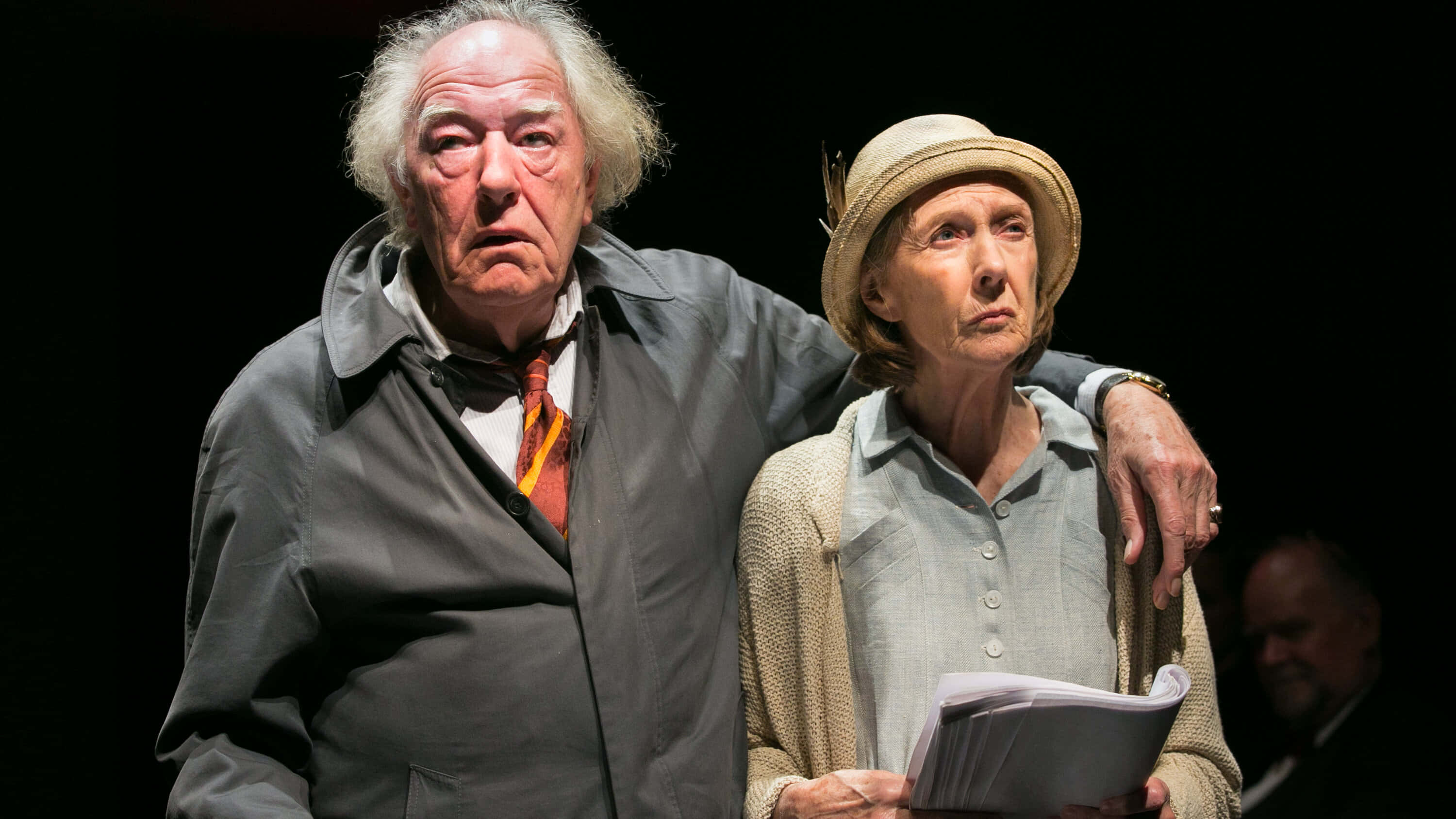 theatrical performance, two actors on stage, elderly man in a gray coat, 2K Desktop Wallpaper
