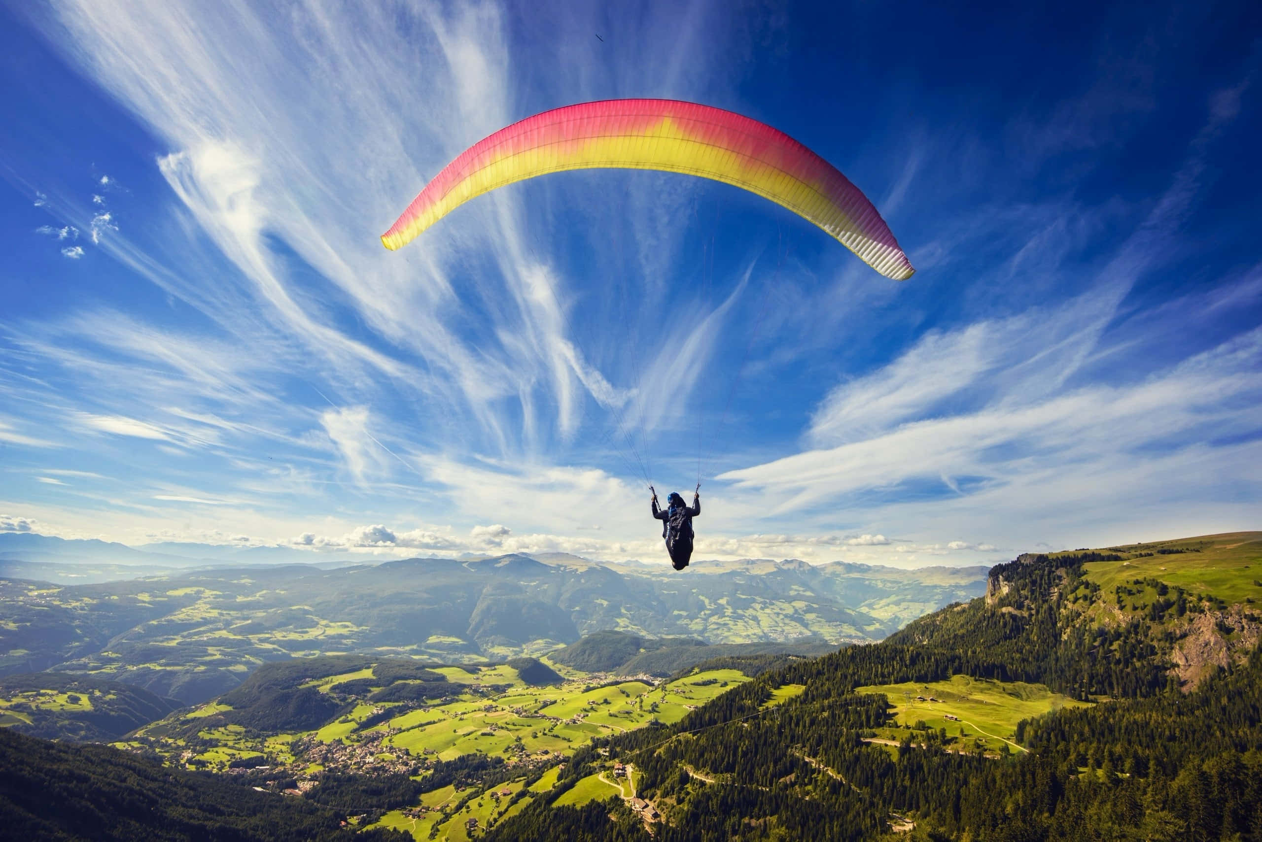 paraglider, vibrant red yellow canopy, green valley, 2K Desktop Wallpaper