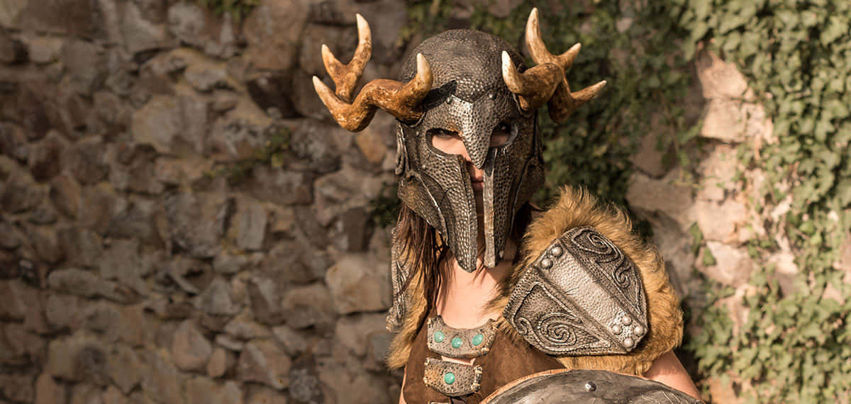 Aela The Huntress, deer-horned helmet, mossy stone wall, SD Desktop Wallpaper