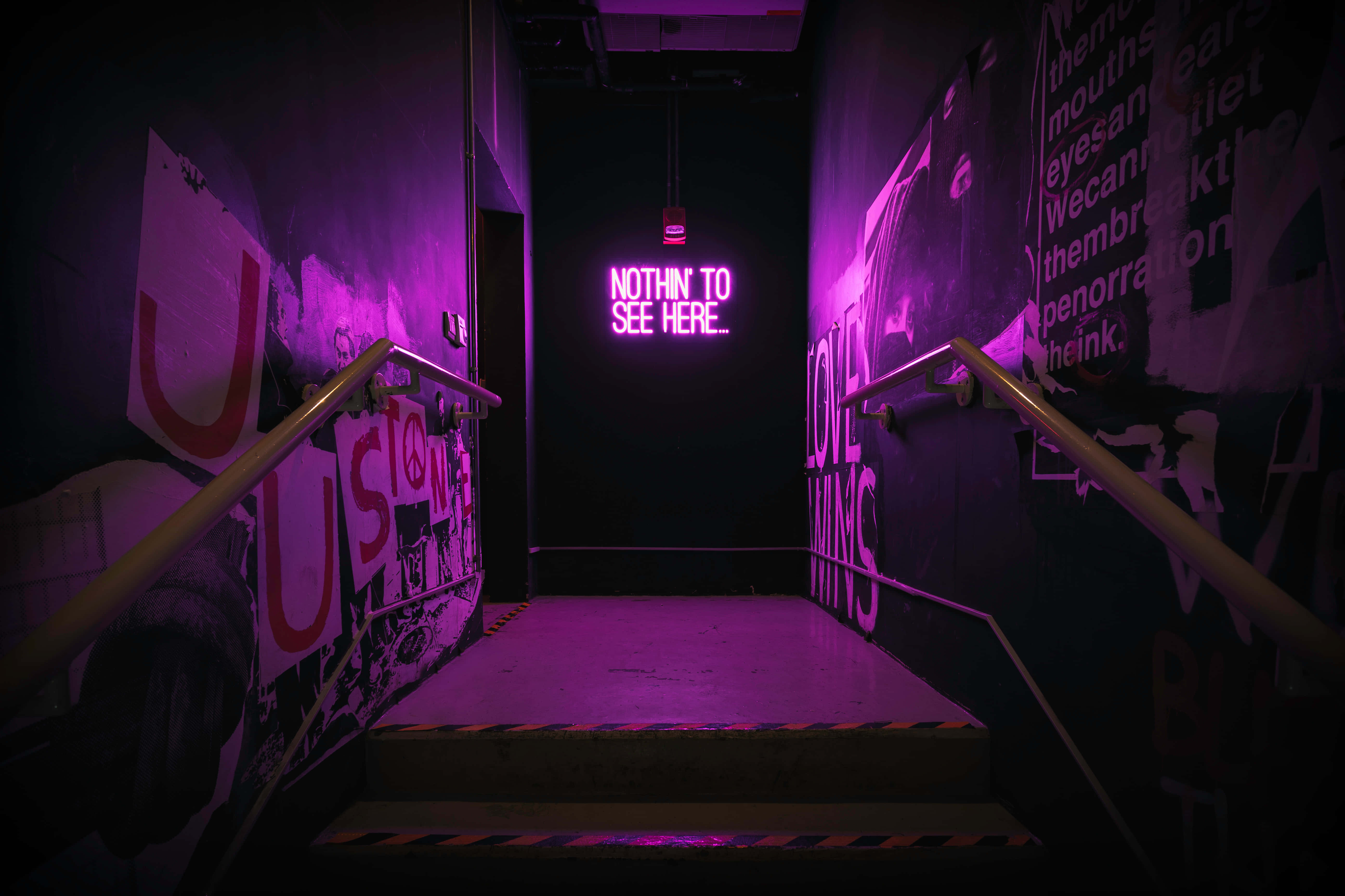 purple neon light, graffiti-covered walls, glowing sign reading 'NOTHIN TO SEE HERE', 5K Desktop Wallpaper