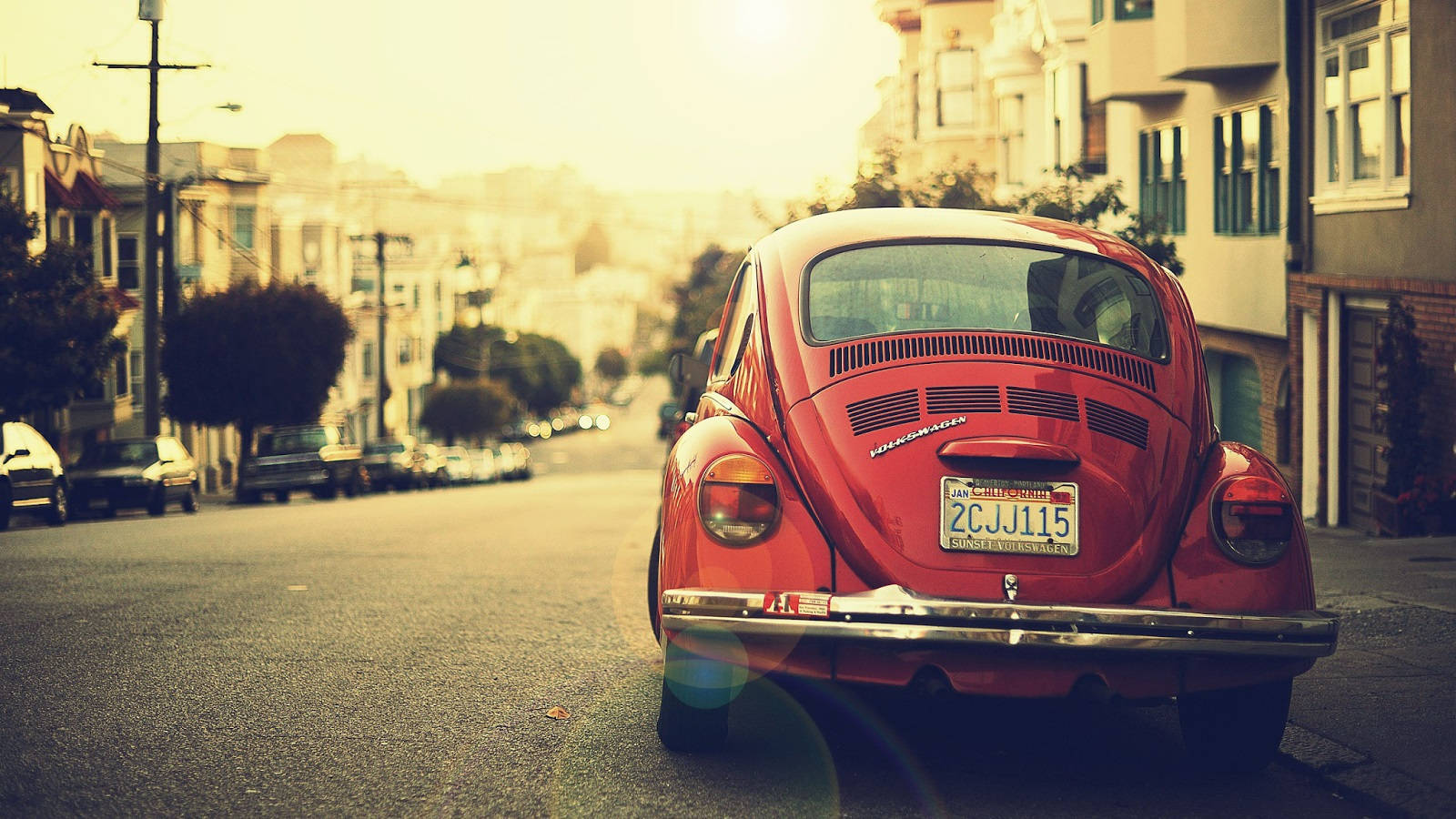 vintage red Volkswagen Beetle, sun-drenched hillside street, warm golden light, HD Desktop Wallpaper
