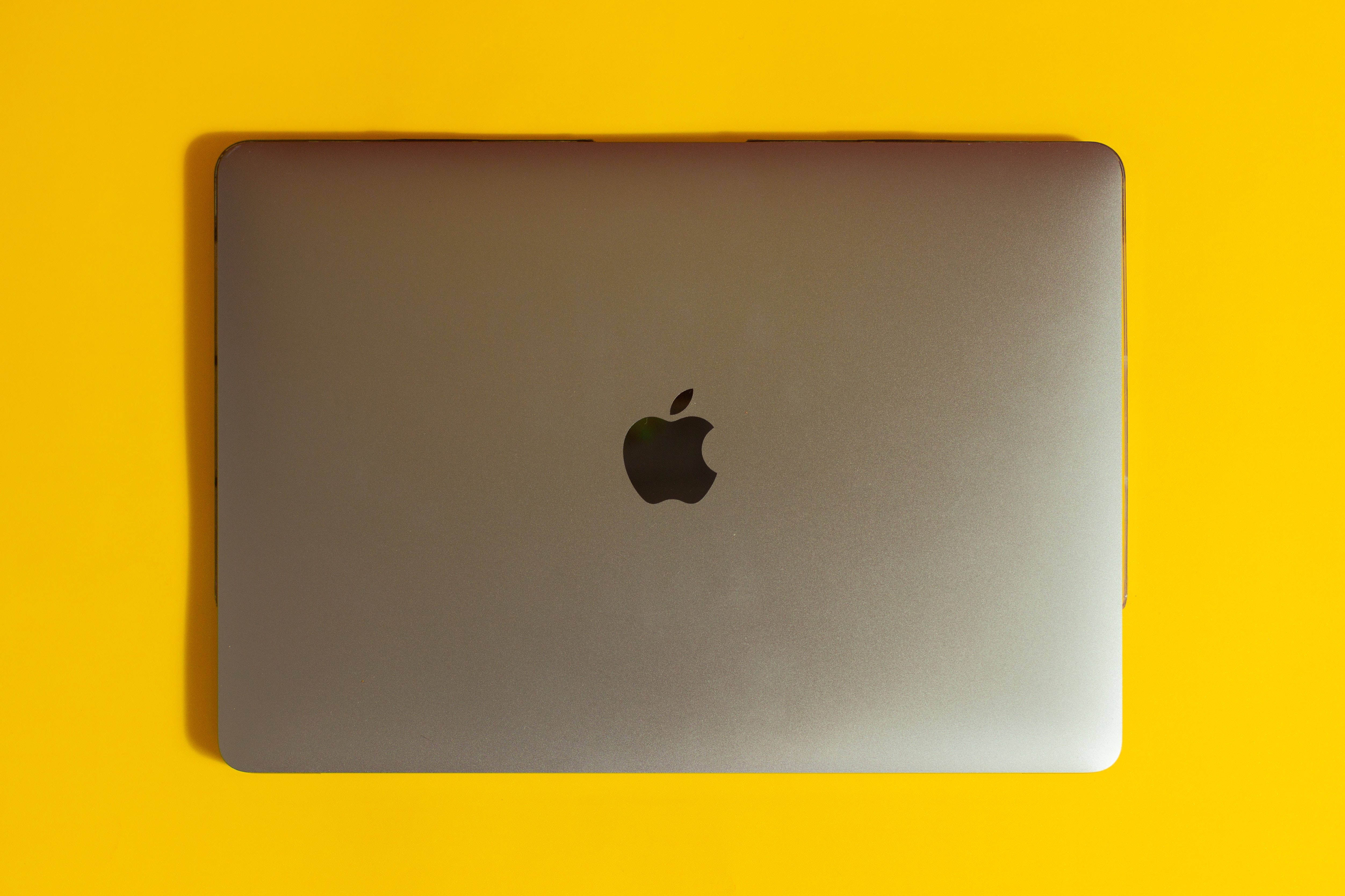 silver MacBook, vibrant yellow background, soft shadow, 4K Desktop Wallpaper