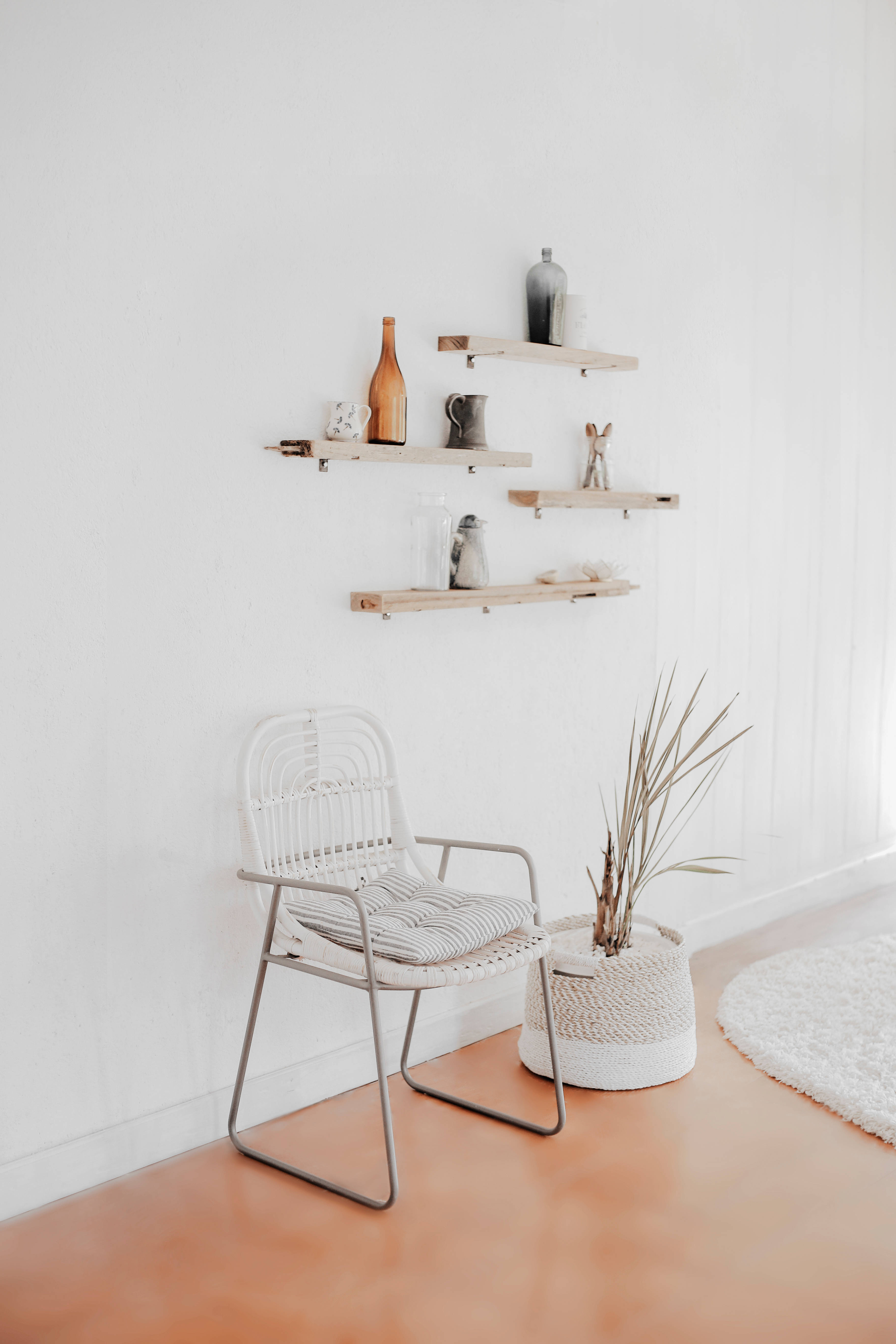 minimalist white woven chair, potted plant, floating wooden shelves, 5K Phone Wallpaper