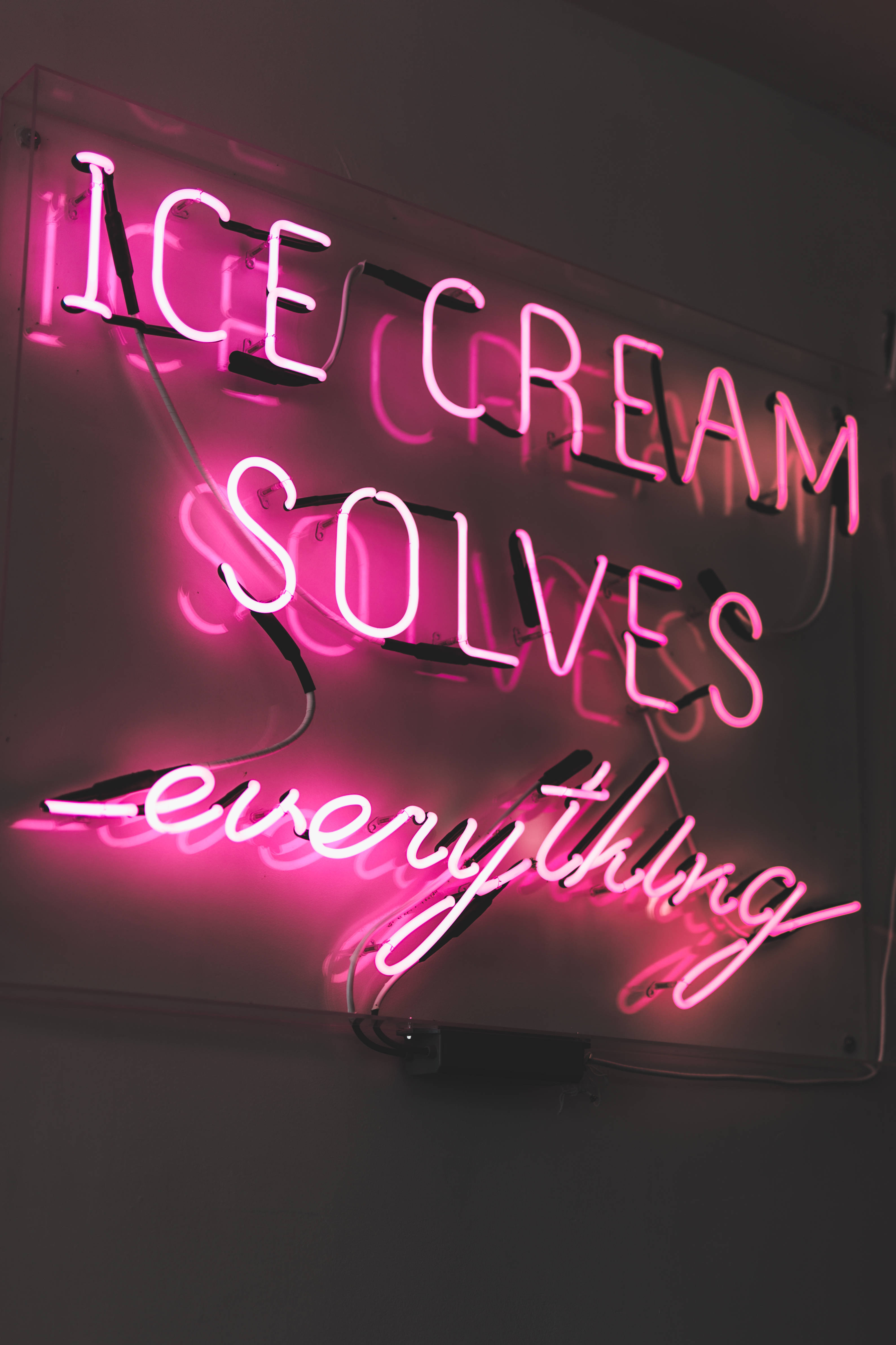 ice cream solves everything, glowing pink neon sign, dark wall, 4K Phone Wallpaper