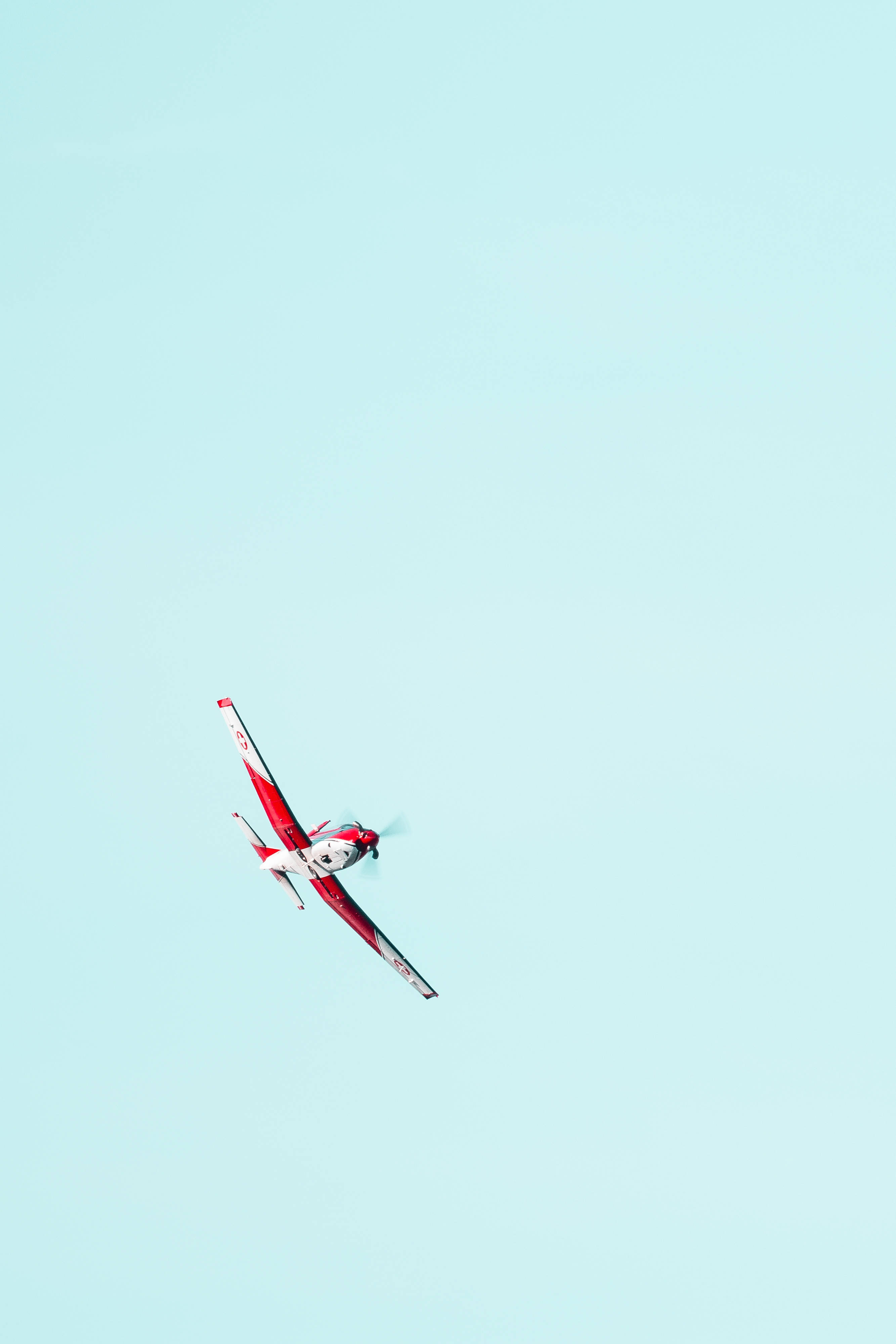 soaring red airplane, red and white stunt airplane, vast pale blue sky, 4K Phone Wallpaper