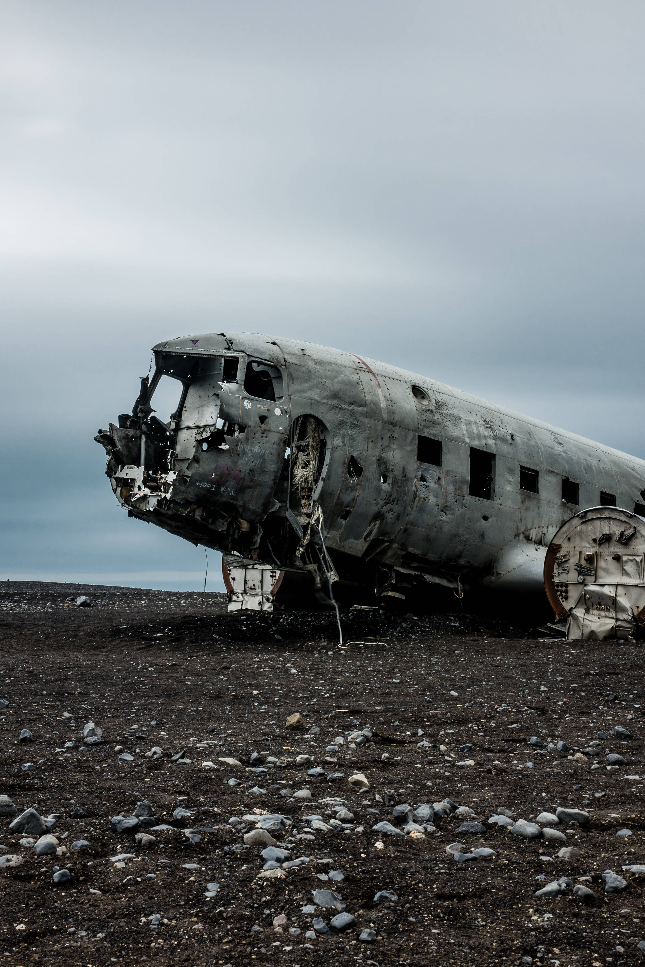 airplane fuselage, rusted, rocky black sand field, 4K Phone Wallpaper