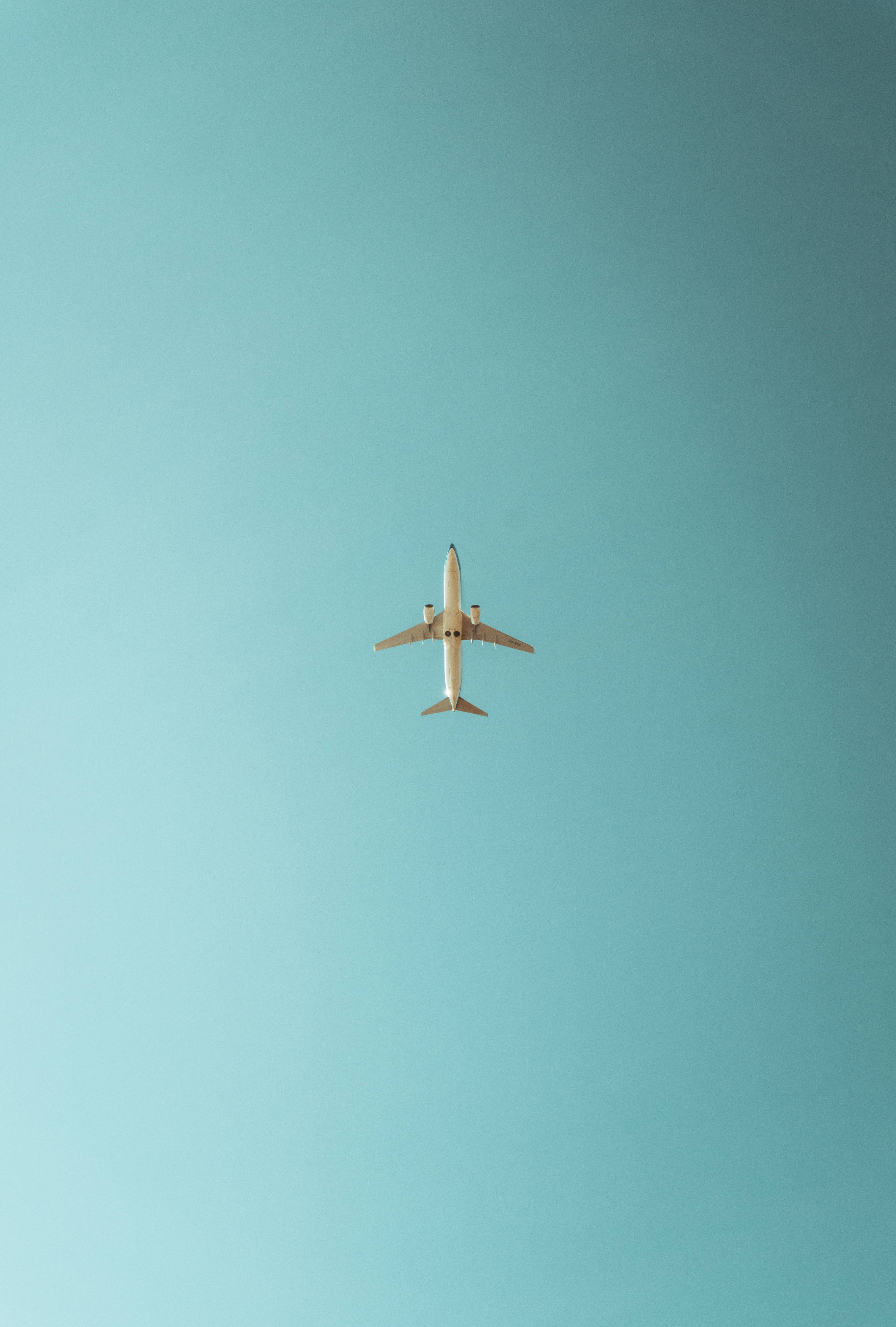 minimalist airplane iPhone, white airplane, vast clear turquoise sky, 5K Phone Wallpaper