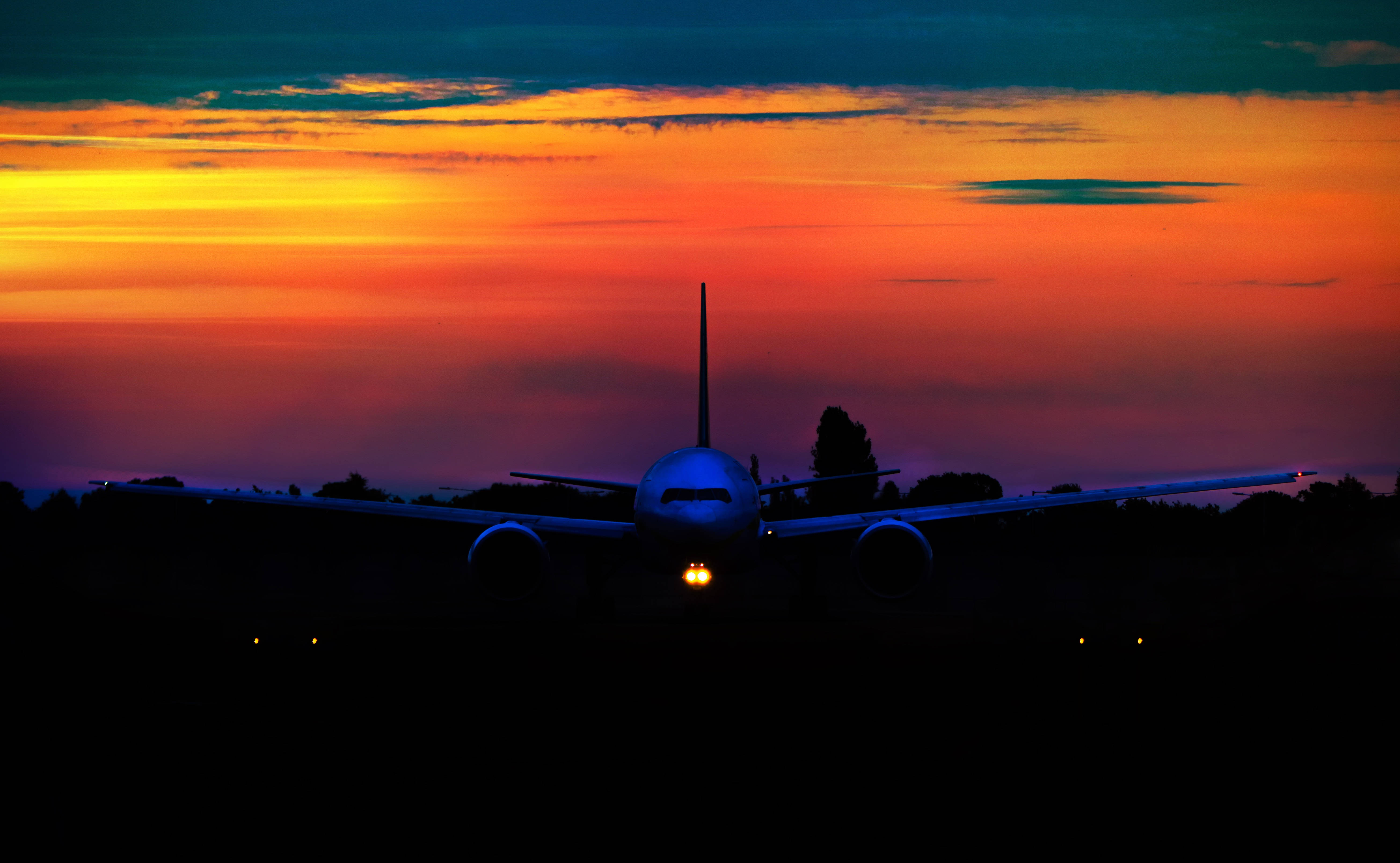passenger jet, fiery sunset sky, glowing cockpit lights, 5K Desktop Wallpaper
