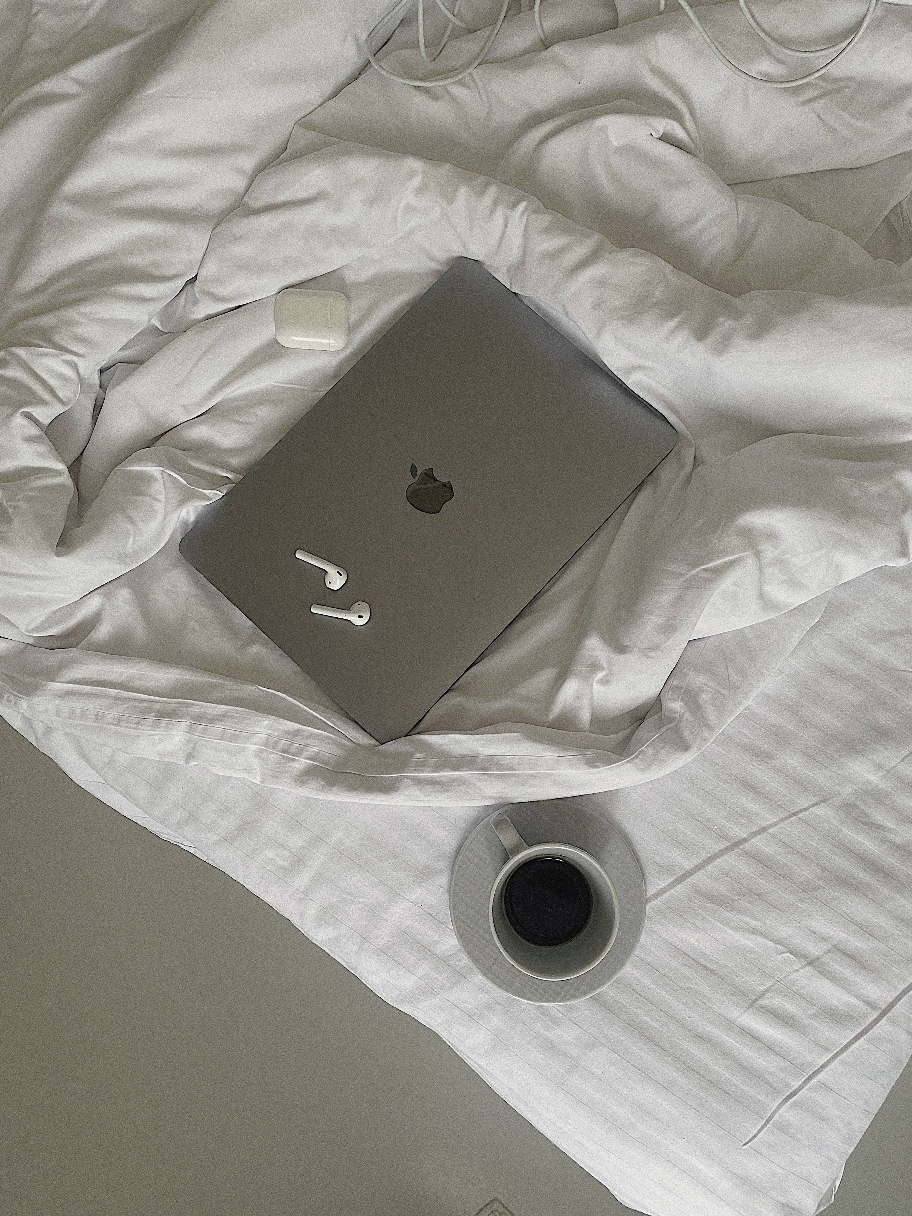 silver laptop, white earbuds, rumpled white sheets, 4K Phone Wallpaper