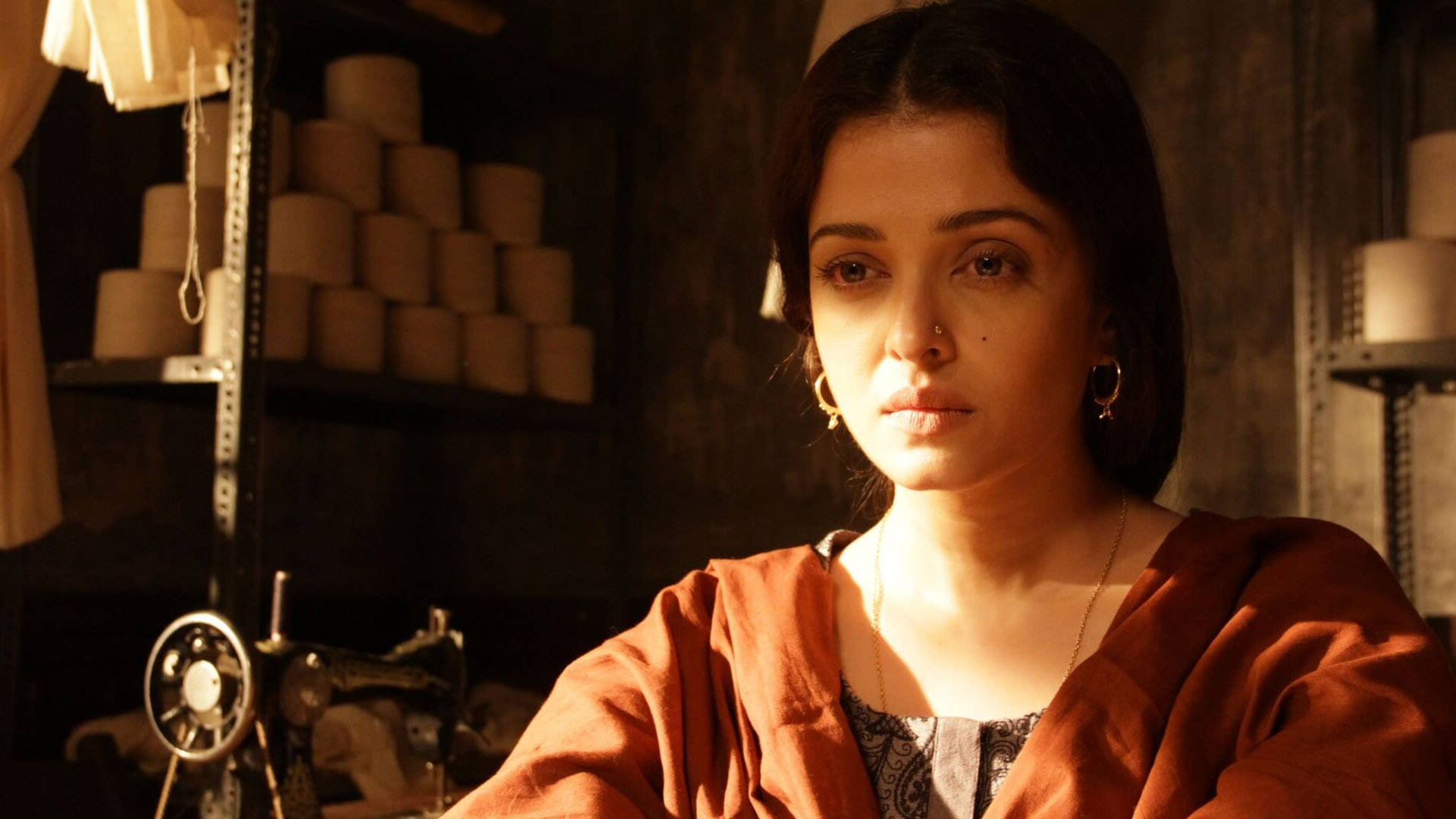 Aishwarya Rai, orange robe, warmly lit workshop, Full HD Desktop Wallpaper