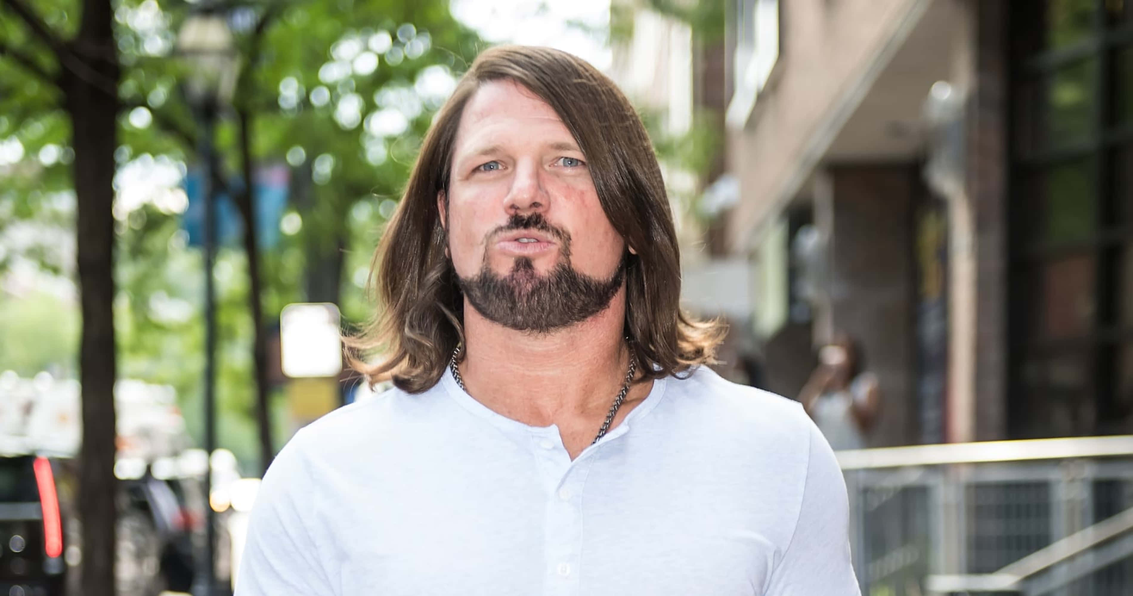 AJ Styles, sunlit city sidewalk, trees, 2K Desktop Wallpaper