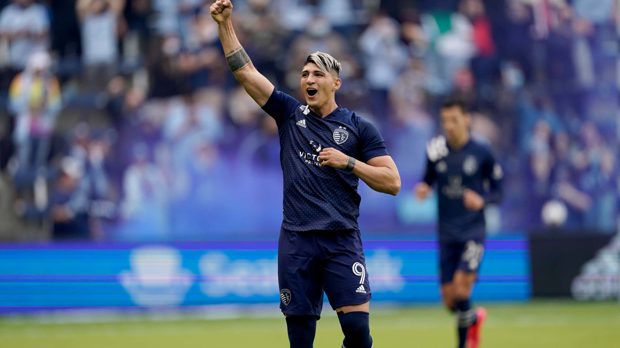 Alan Pulido, dark blue uniform, vibrant green field, 2K Desktop Wallpaper
