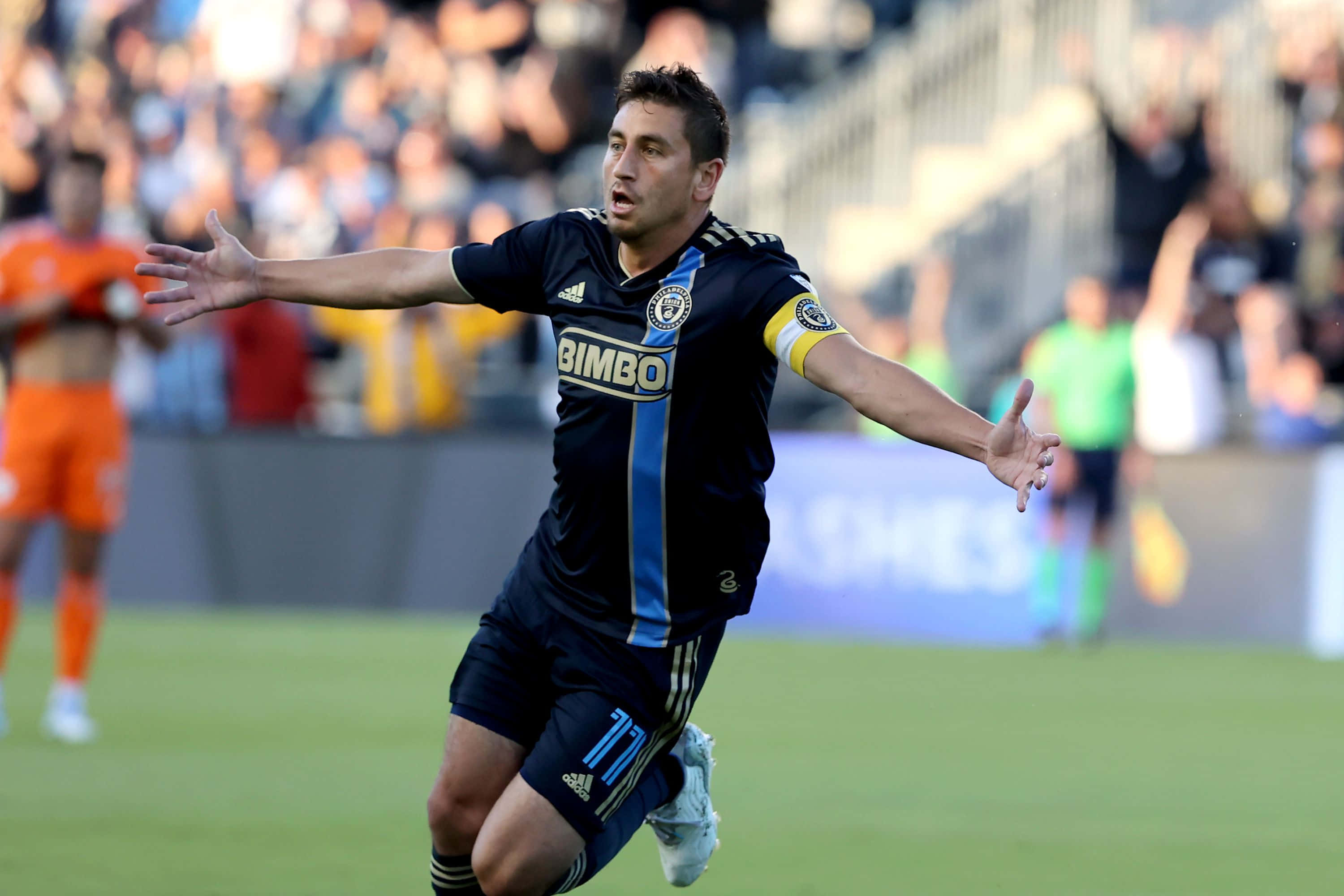 Alejandro Bedoya, dark blue jersey, sunlit green field, 2K Desktop Wallpaper