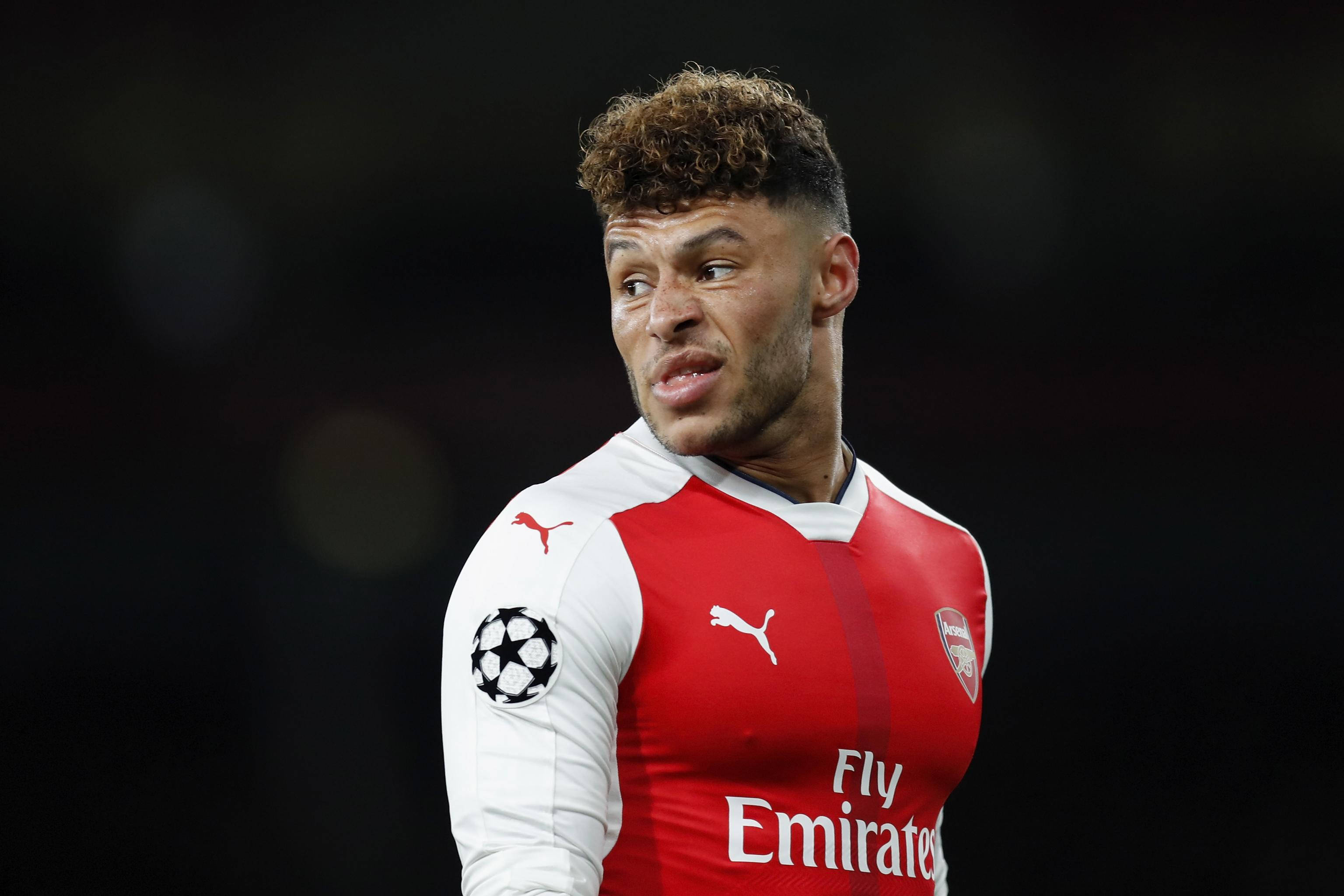 Alex Oxlade-Chamberlain, red and white Arsenal jersey, dark blurred stadium background, 2K Desktop Wallpaper