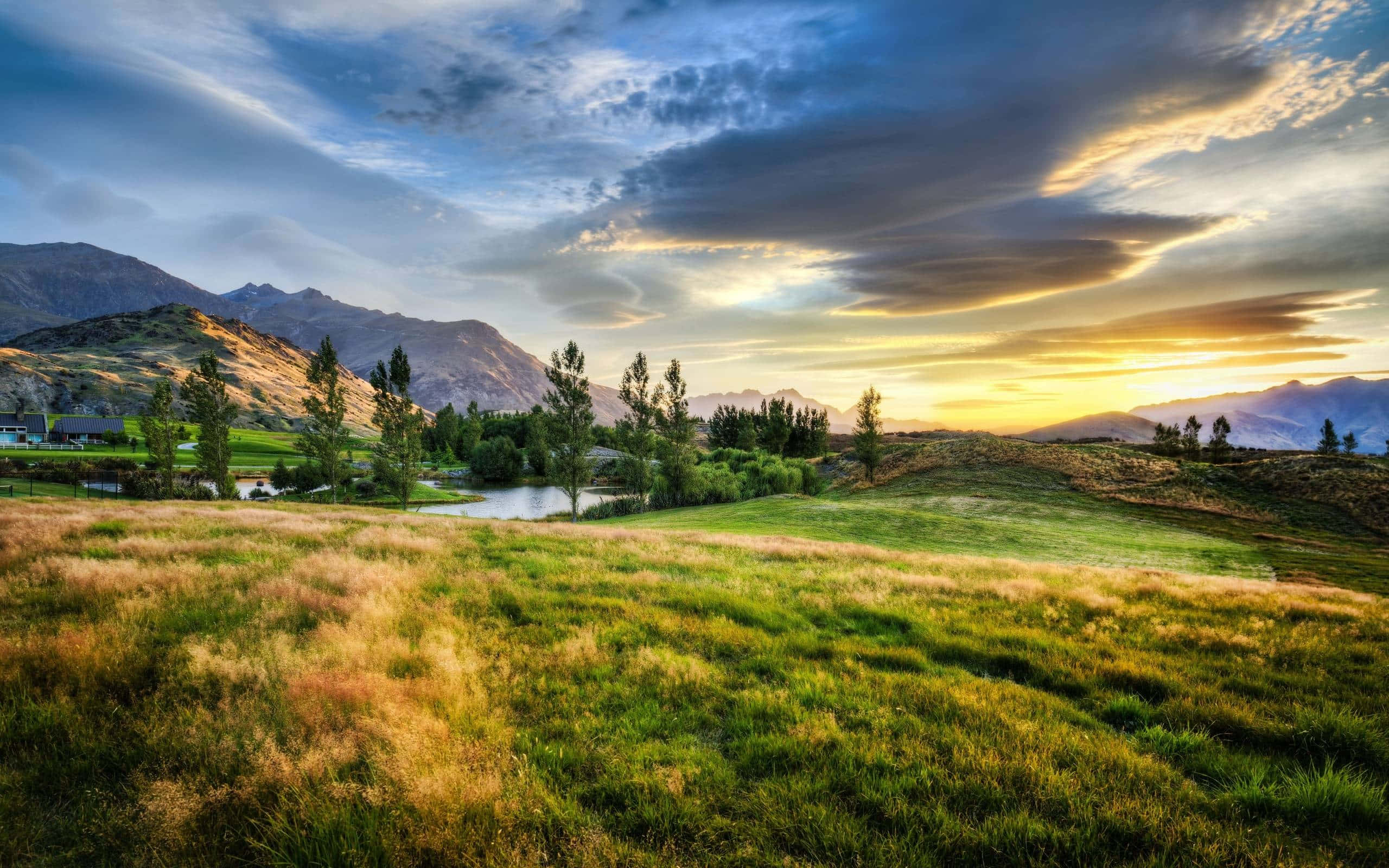 Golden sunset, grassy field, distant mountains, 2K Desktop Wallpaper