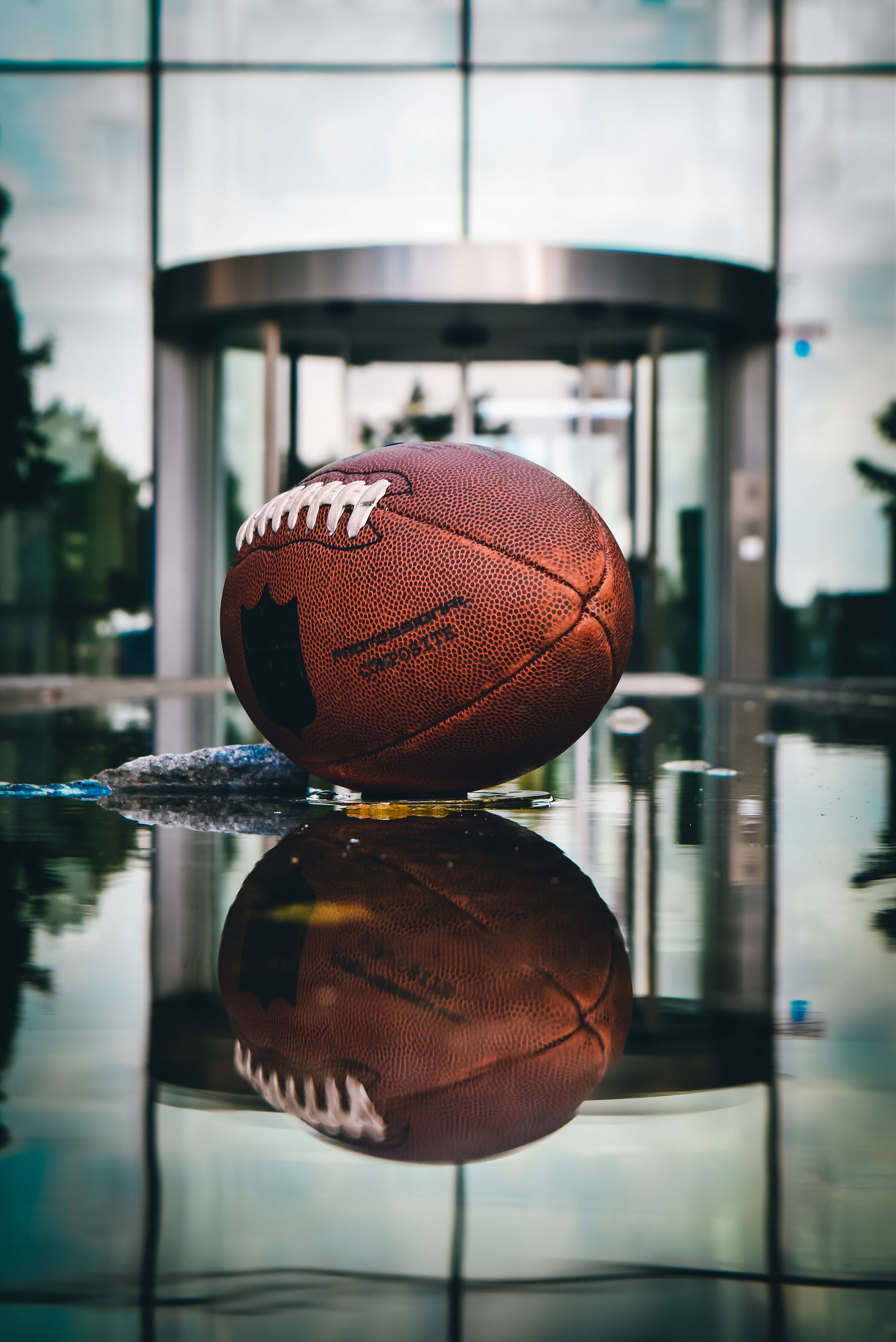 American Football, brown leather football, wet glass floor, 4K Phone Wallpaper