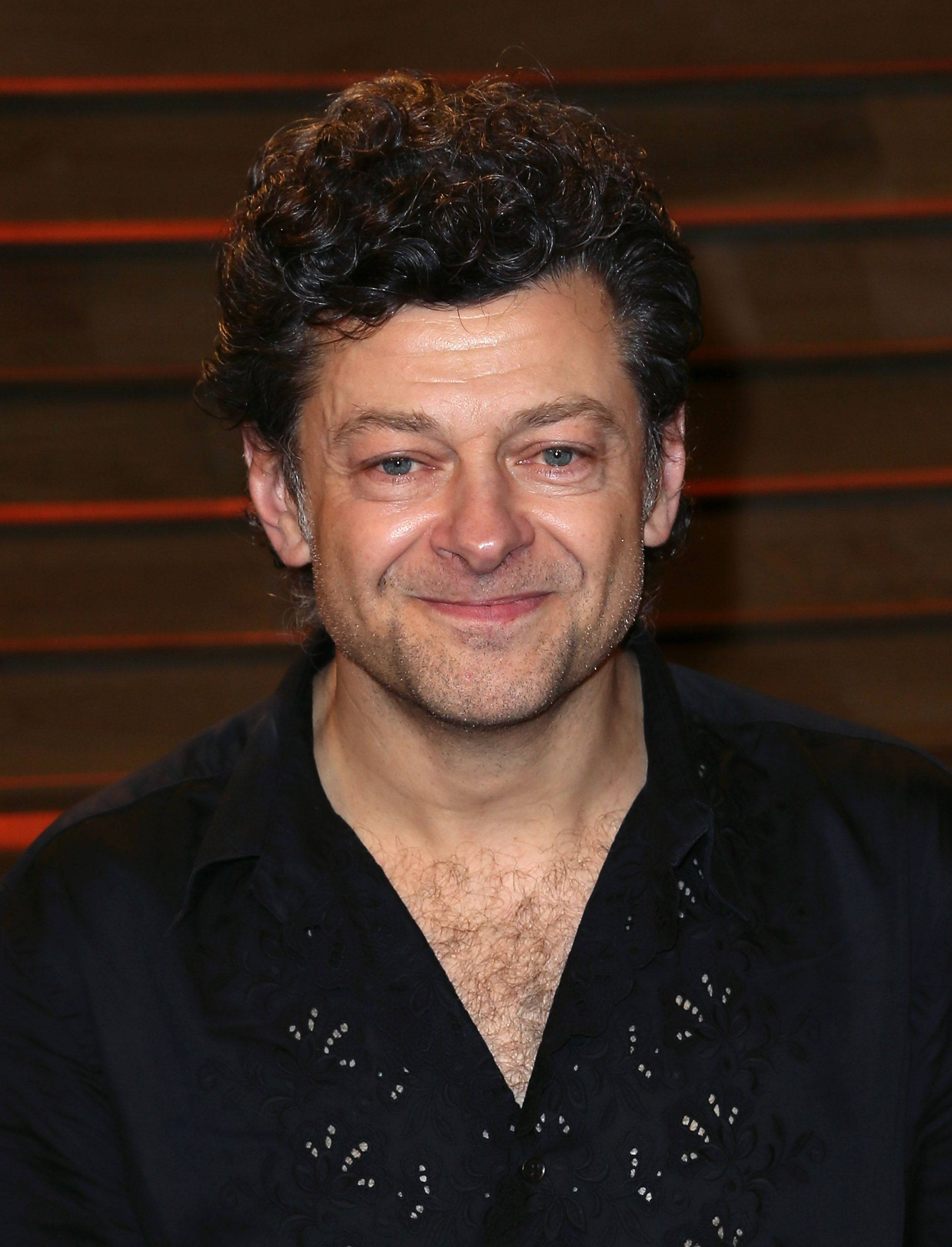 Andy Serkis, black patterned shirt, wooden slat background, 2K Phone Wallpaper
