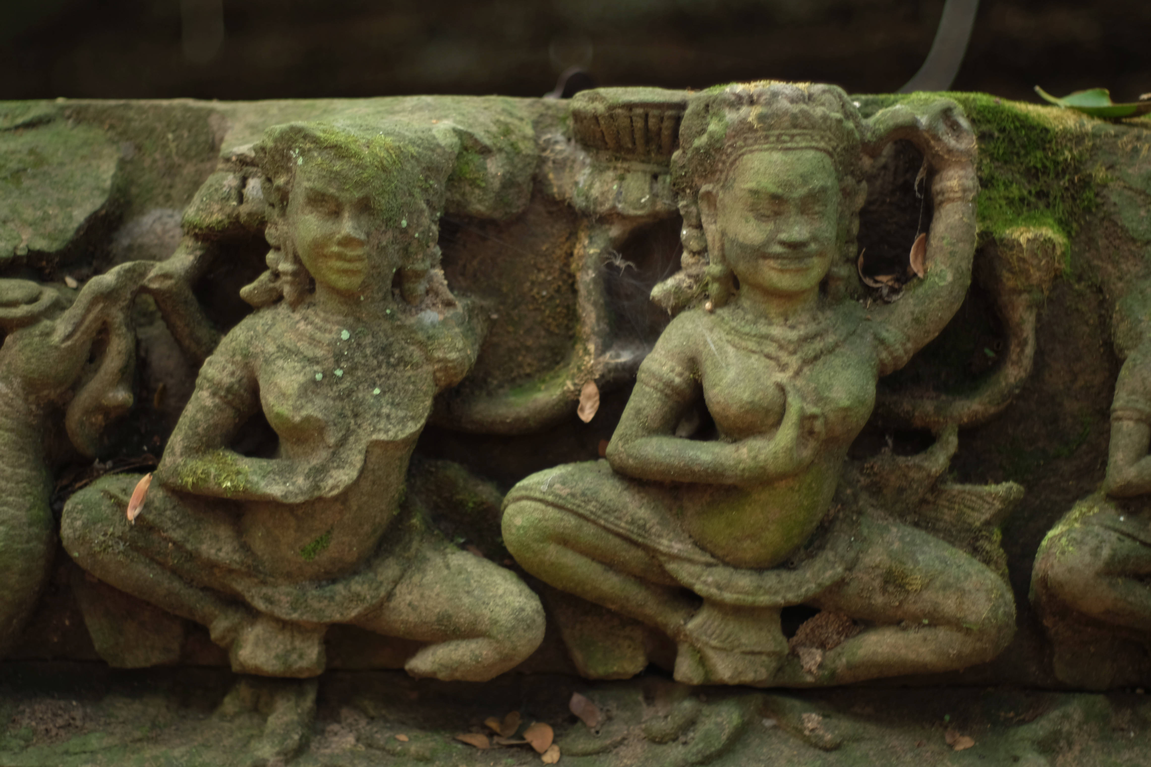 Angkor Wat, moss-covered stone carvings, serene seated figures, 4K Desktop Wallpaper
