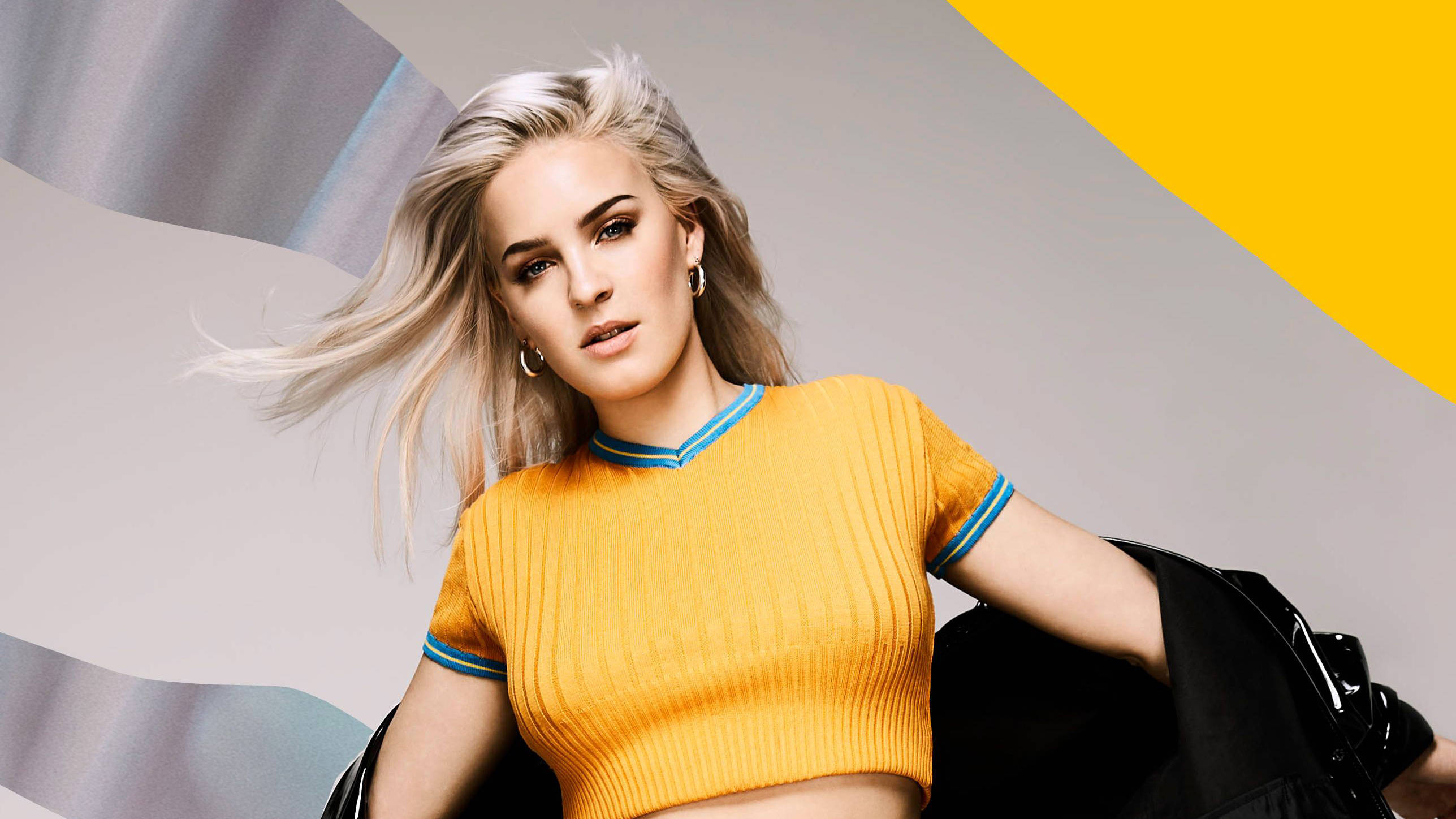 Anne Marie, vibrant yellow ribbed crop top, bold geometric background, 2K Desktop Wallpaper