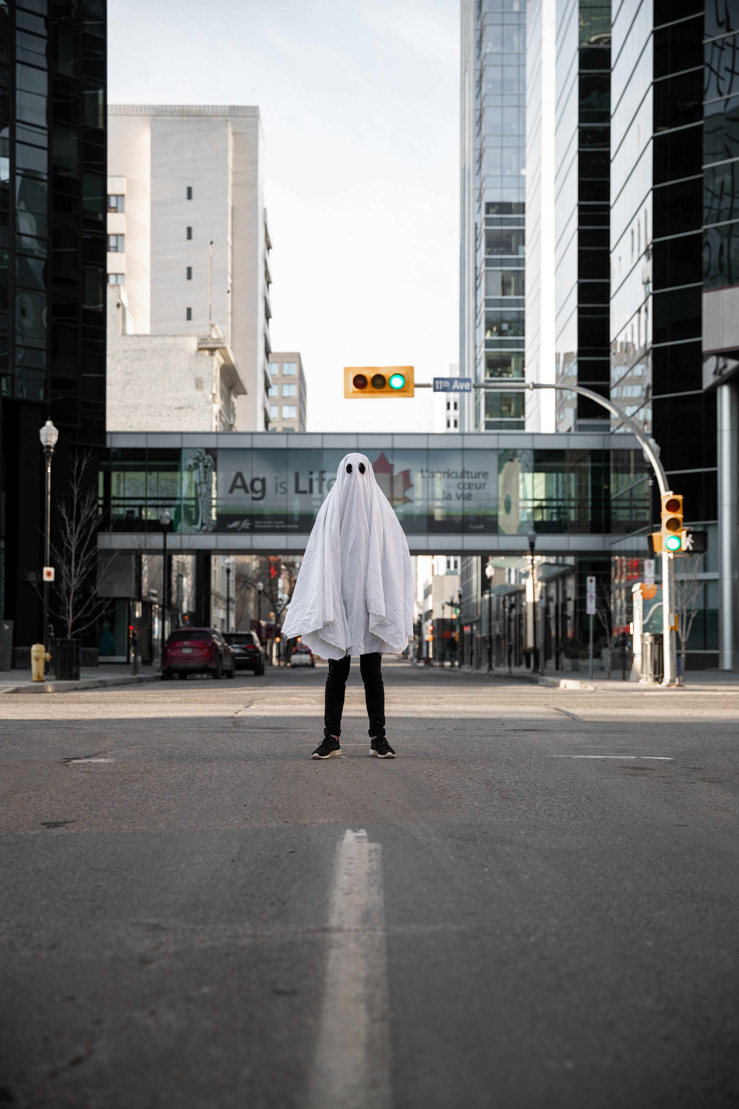 white ghost costume, modern city street, tall glass buildings, 2K Phone Wallpaper