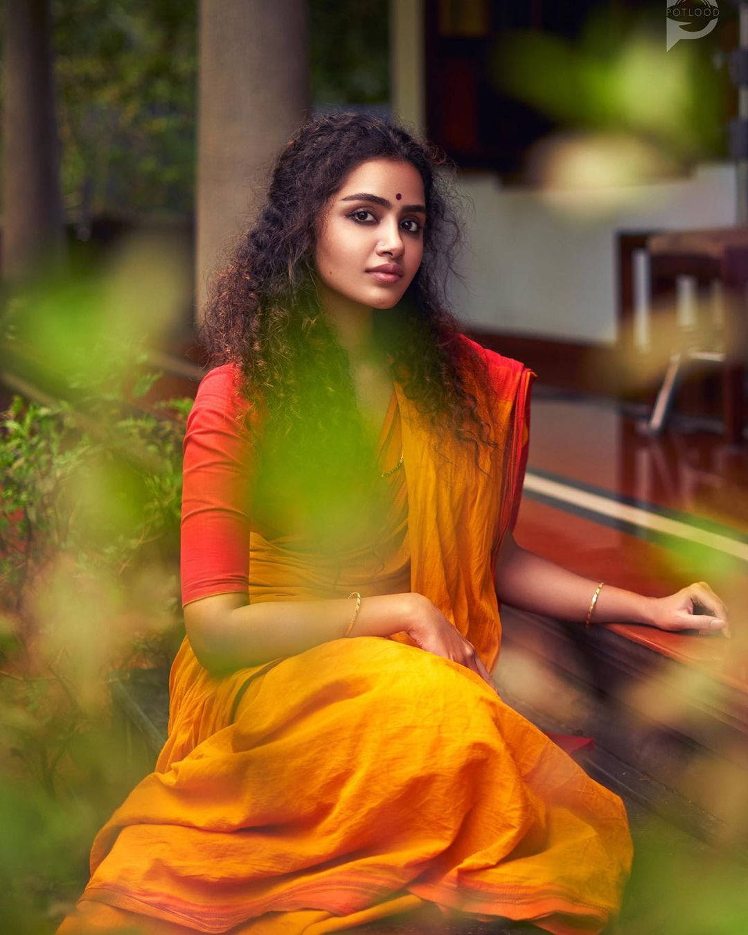 Anupama Parameswaran, vibrant orange and red sari, wooden bench, HD Phone Wallpaper