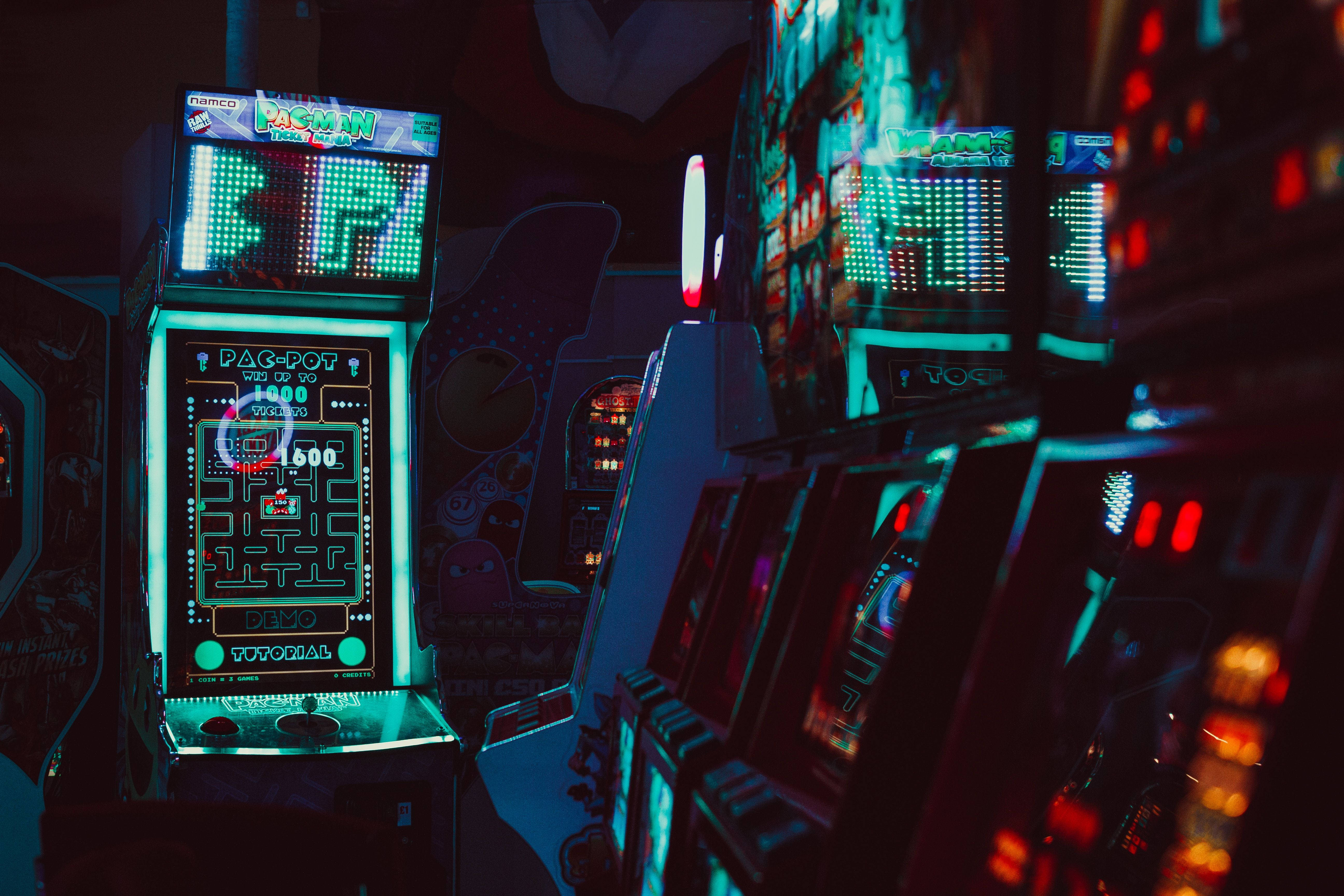 neon-lit arcade machines, dimly lit gaming hall, glowing screens, 5K Desktop Wallpaper