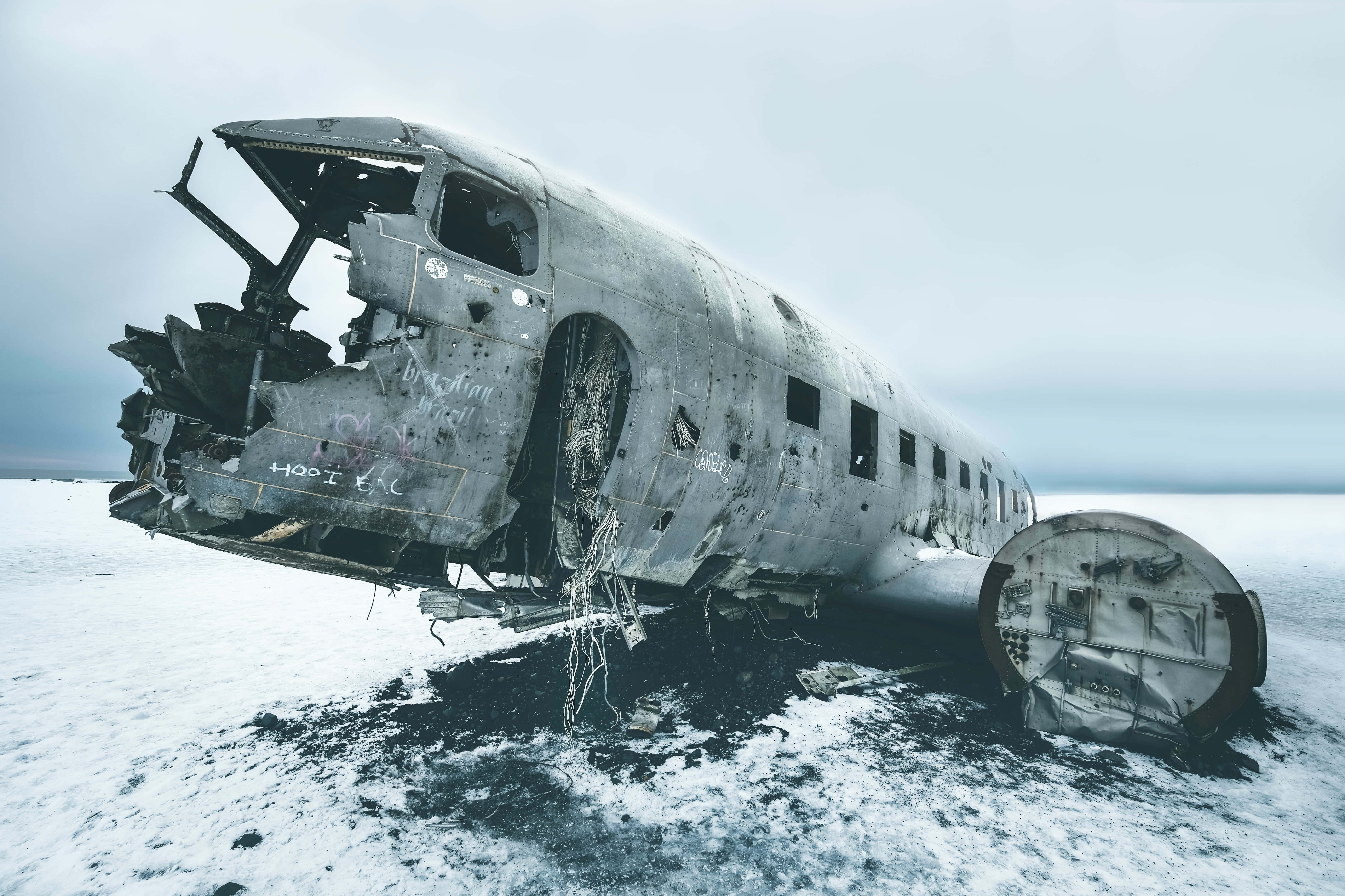 rusted airplane fuselage, vast snowy field, gray sky, 5K Desktop Wallpaper