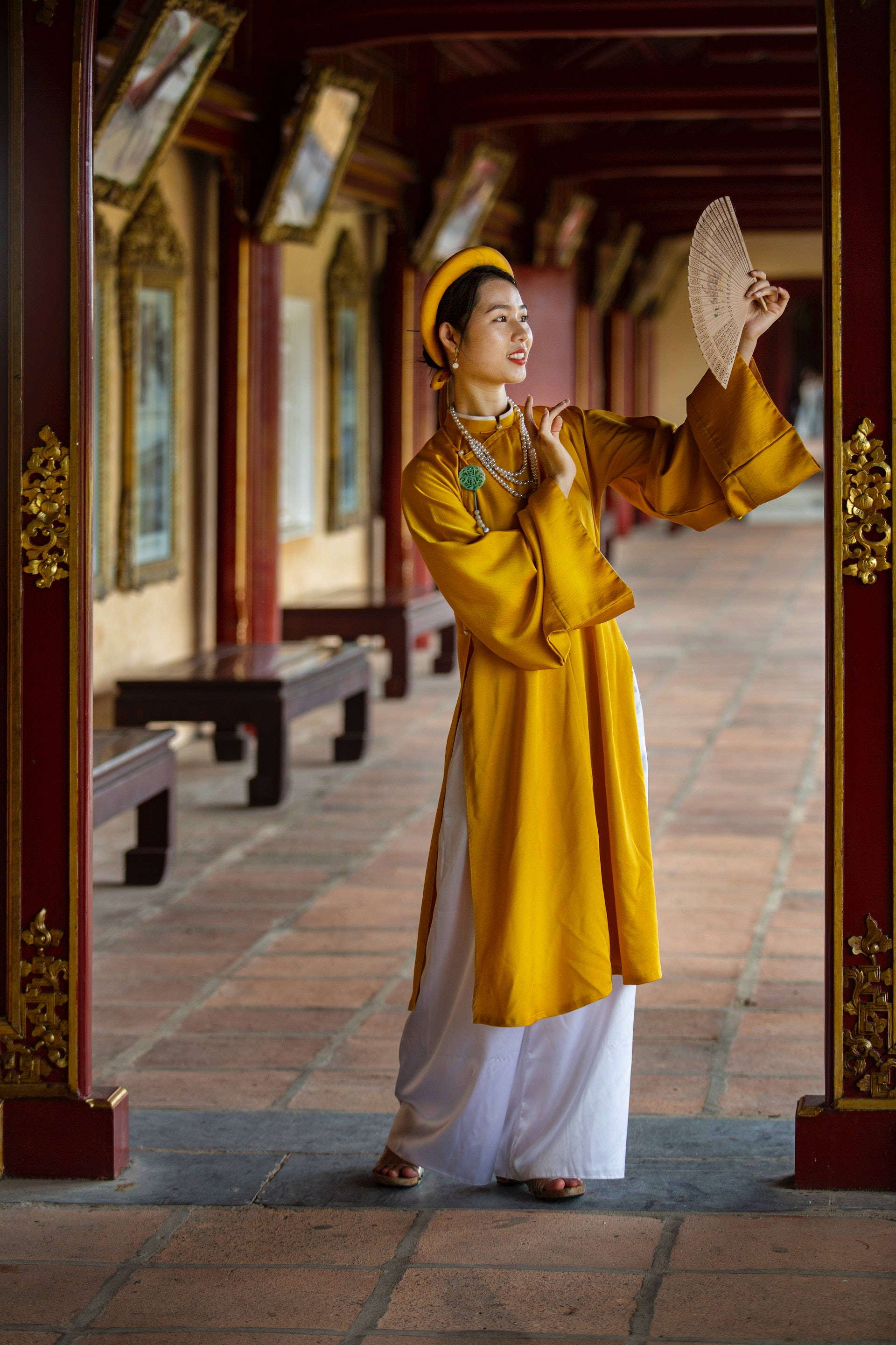 traditional Vietnamese outfit, vibrant yellow, red wooden temple corridor, 2K Phone Wallpaper