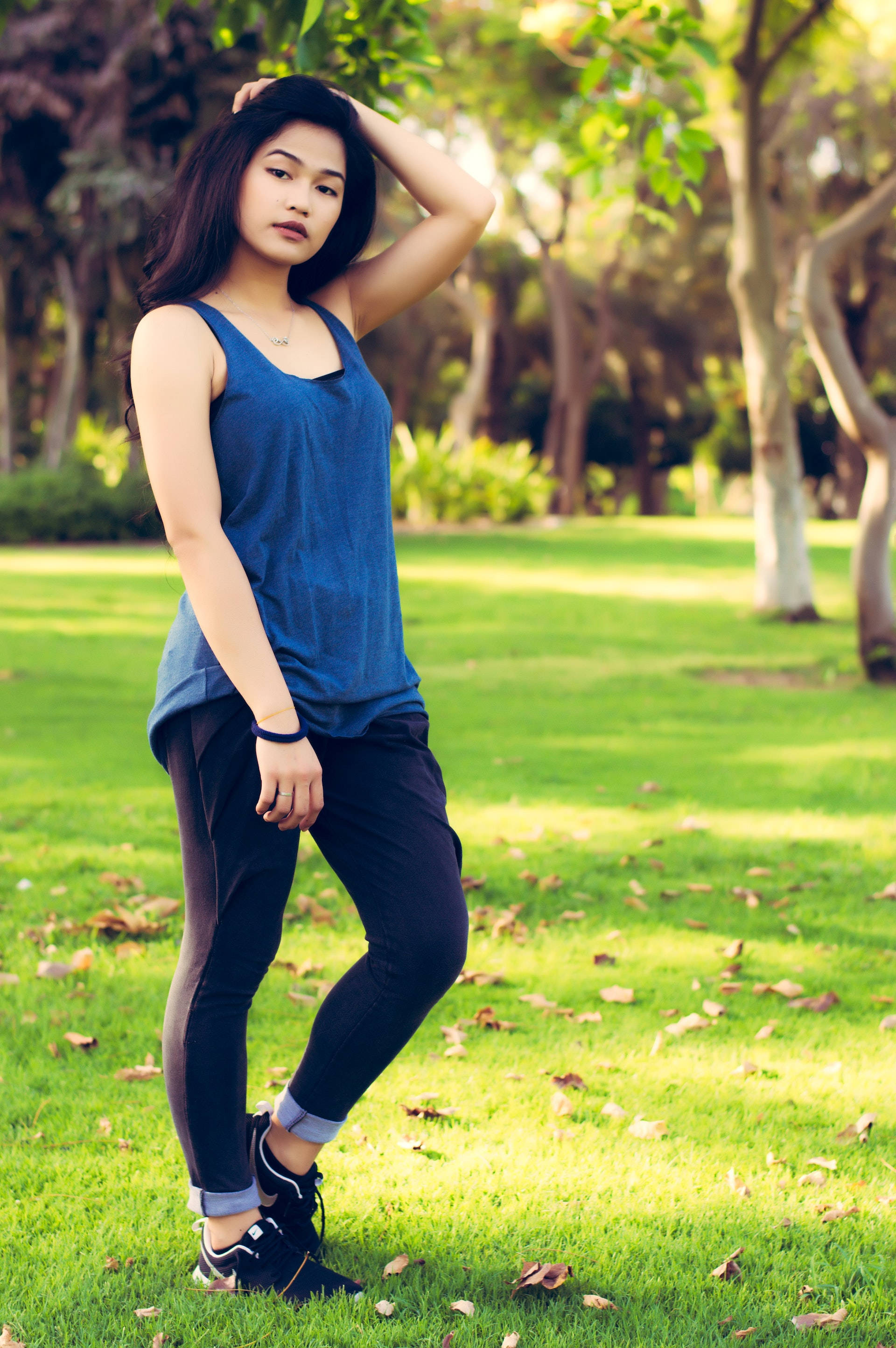 Asian woman, blue tank top, sunlit grass, 2K Phone Wallpaper