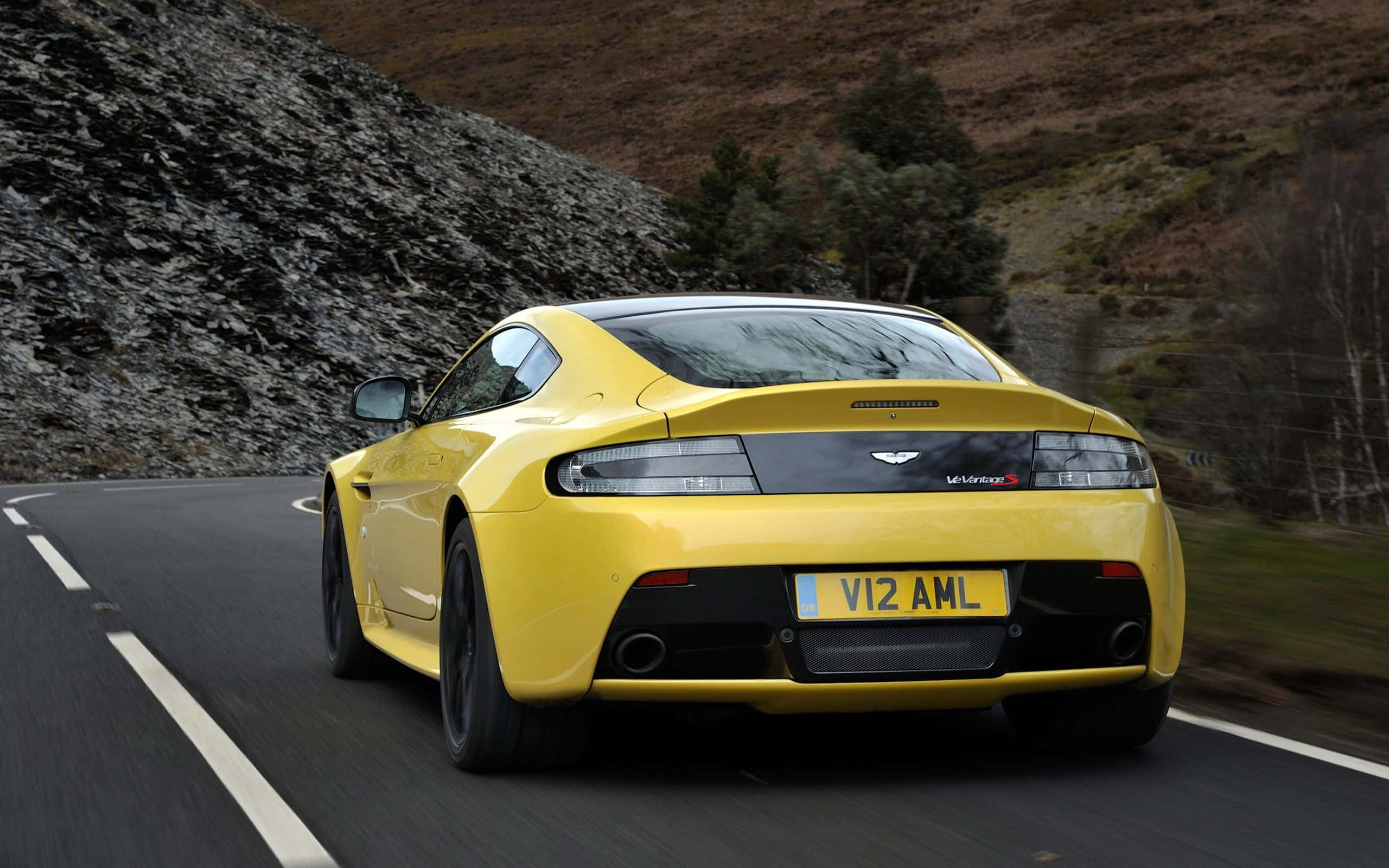 Aston Martin V12 Vantage S, vibrant yellow, winding mountain road, 2K Desktop Wallpaper