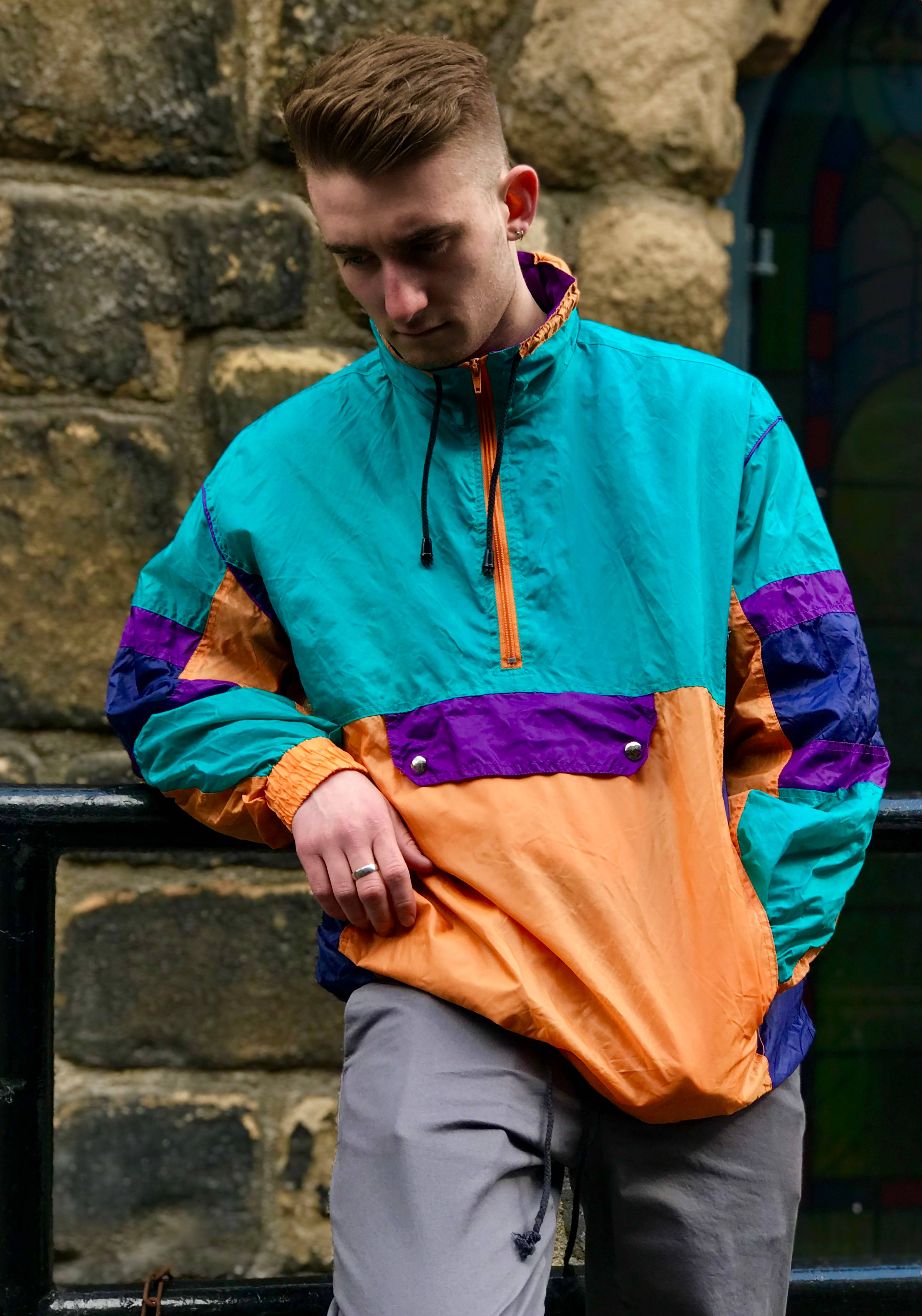 90s-style color-blocked windbreaker, vibrant, stone wall, 2K Phone Wallpaper