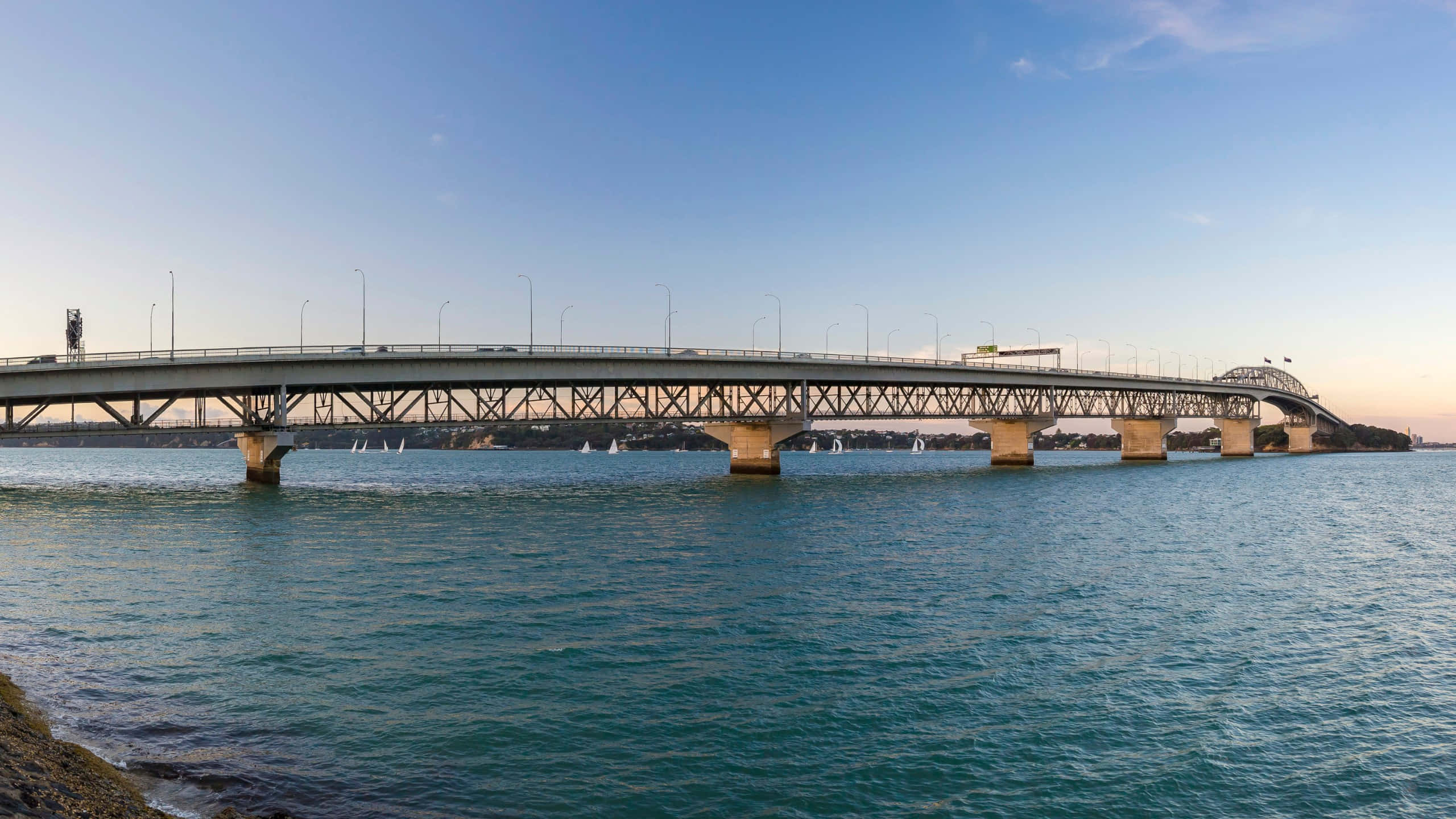 Auckland Harbour Bridge, dusk view, calm turquoise waters, 2K Desktop Wallpaper