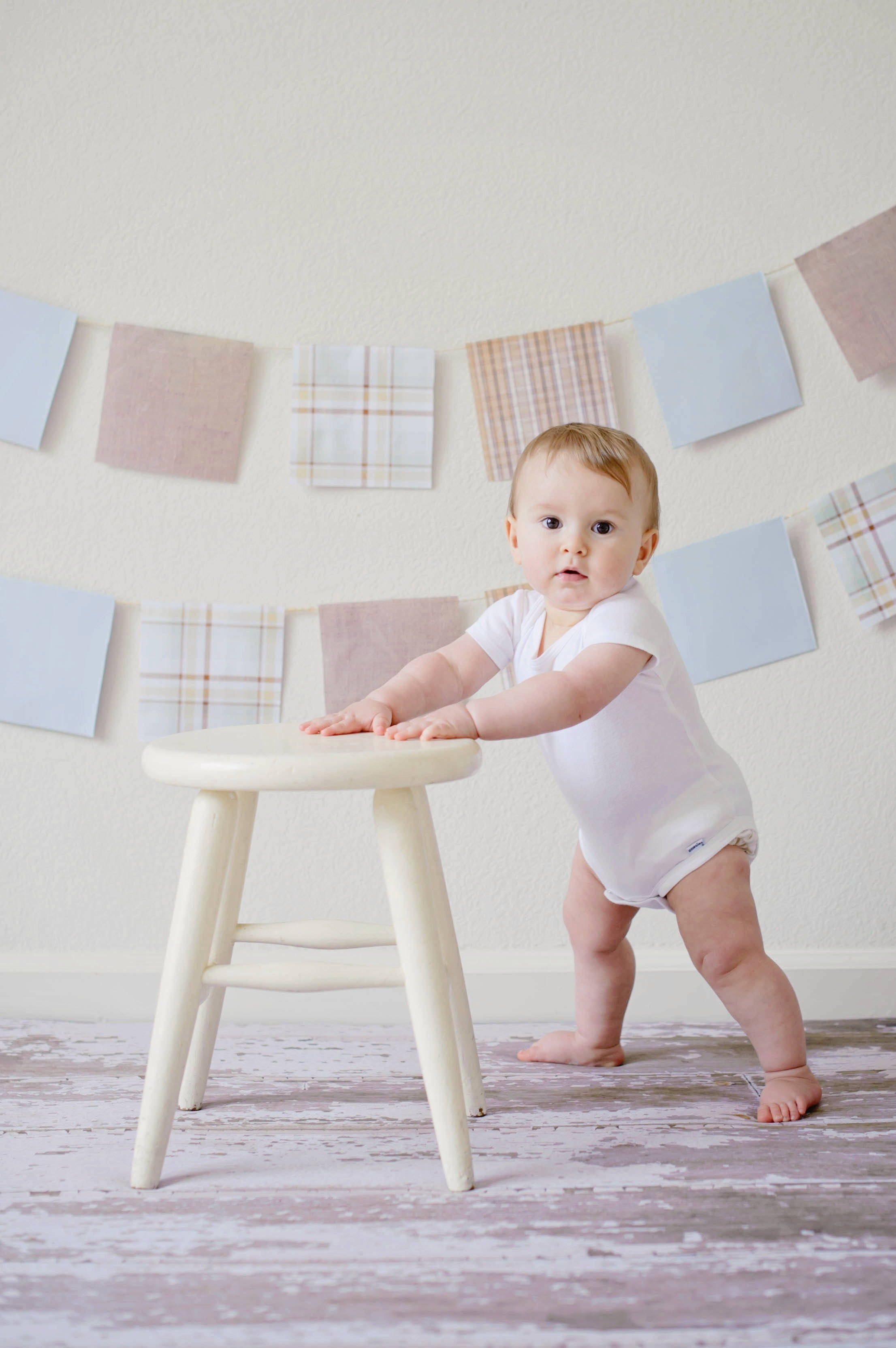 standing baby, white onesie, distressed wooden floor, 2K Phone Wallpaper