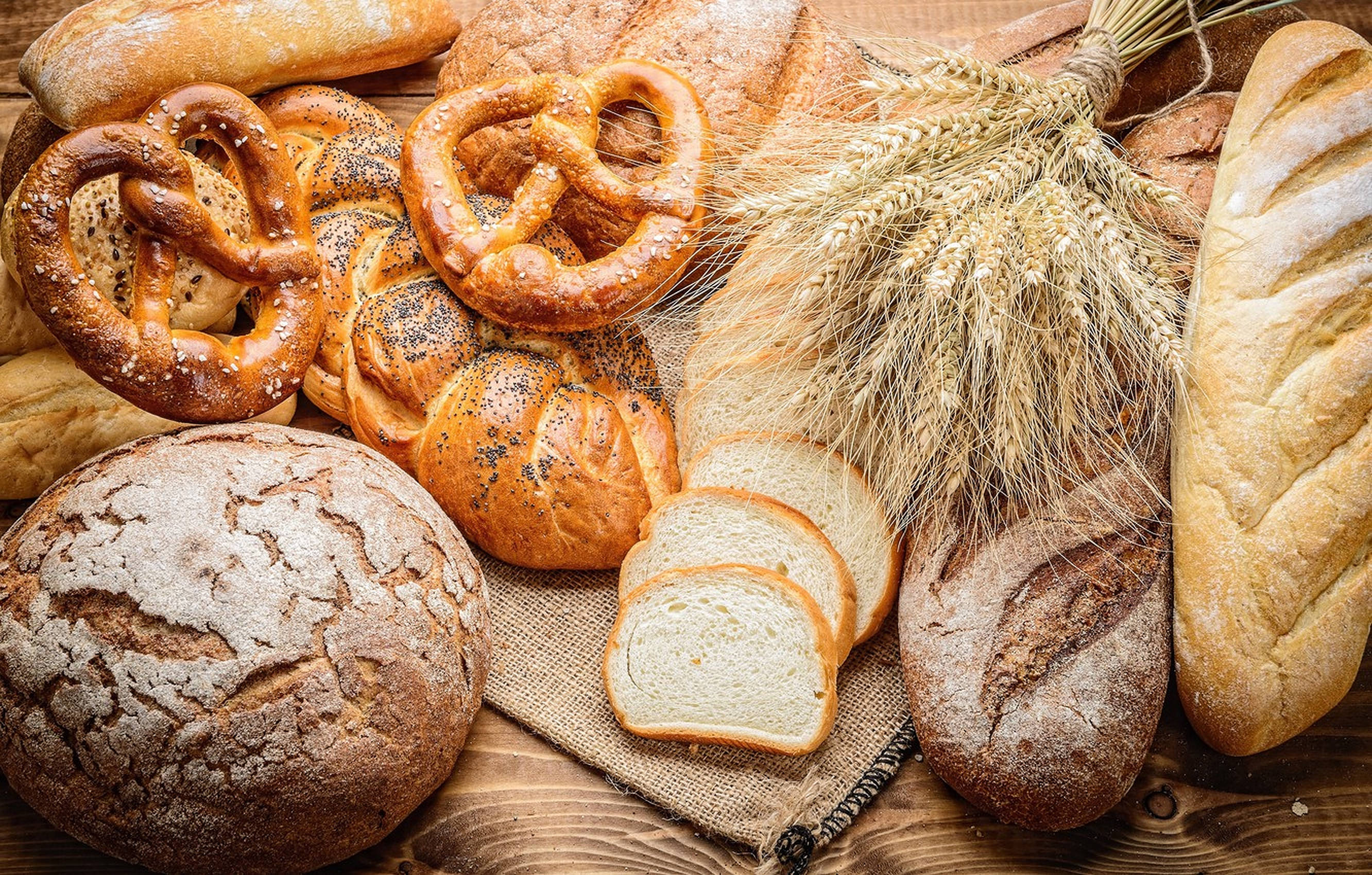 pretzel bakery delicacies, rustic wooden table, freshly baked breads, 2K Desktop Wallpaper
