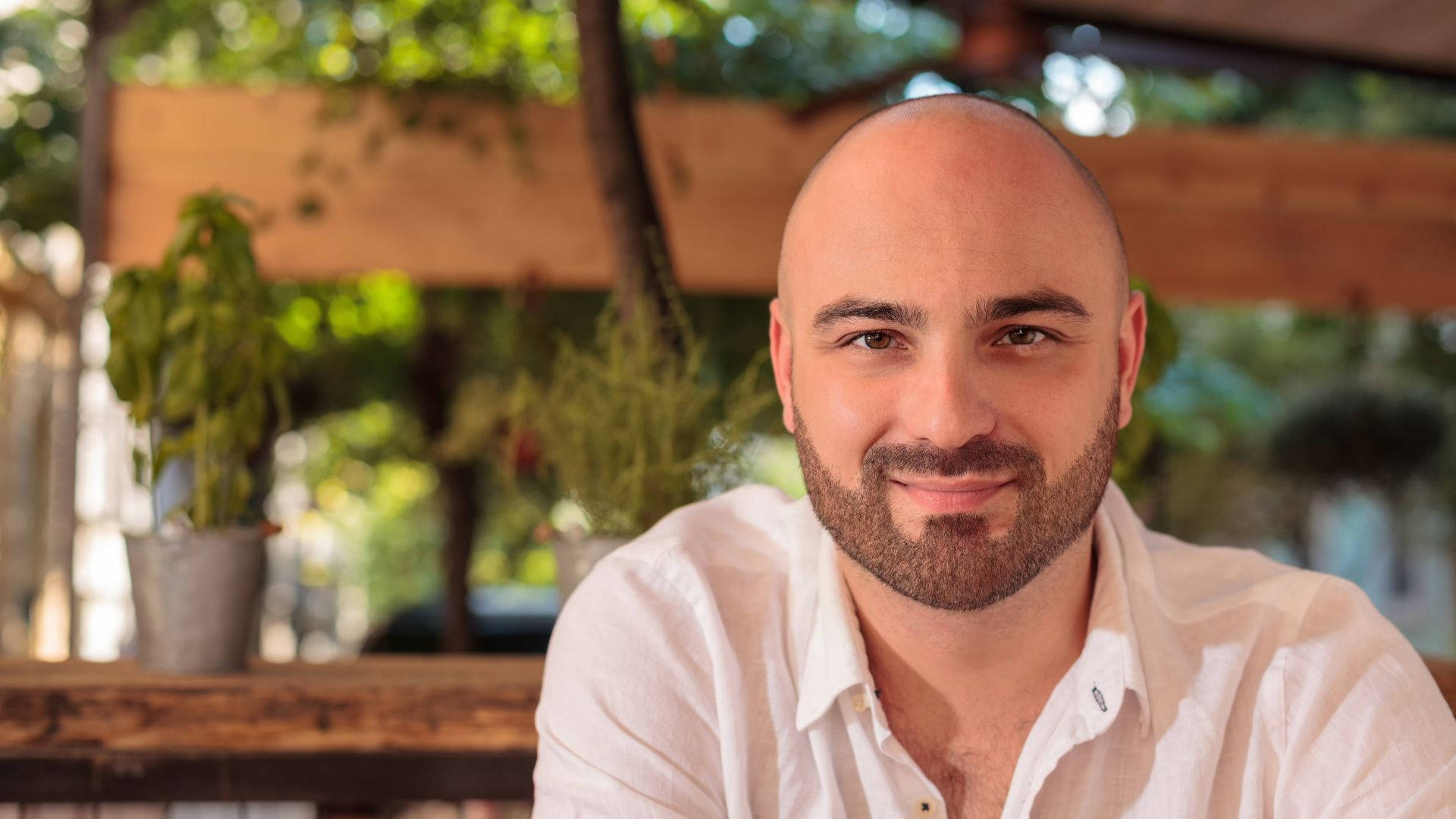 bald man, neatly trimmed beard, sunlit outdoor wooden setting, Full HD Desktop Wallpaper